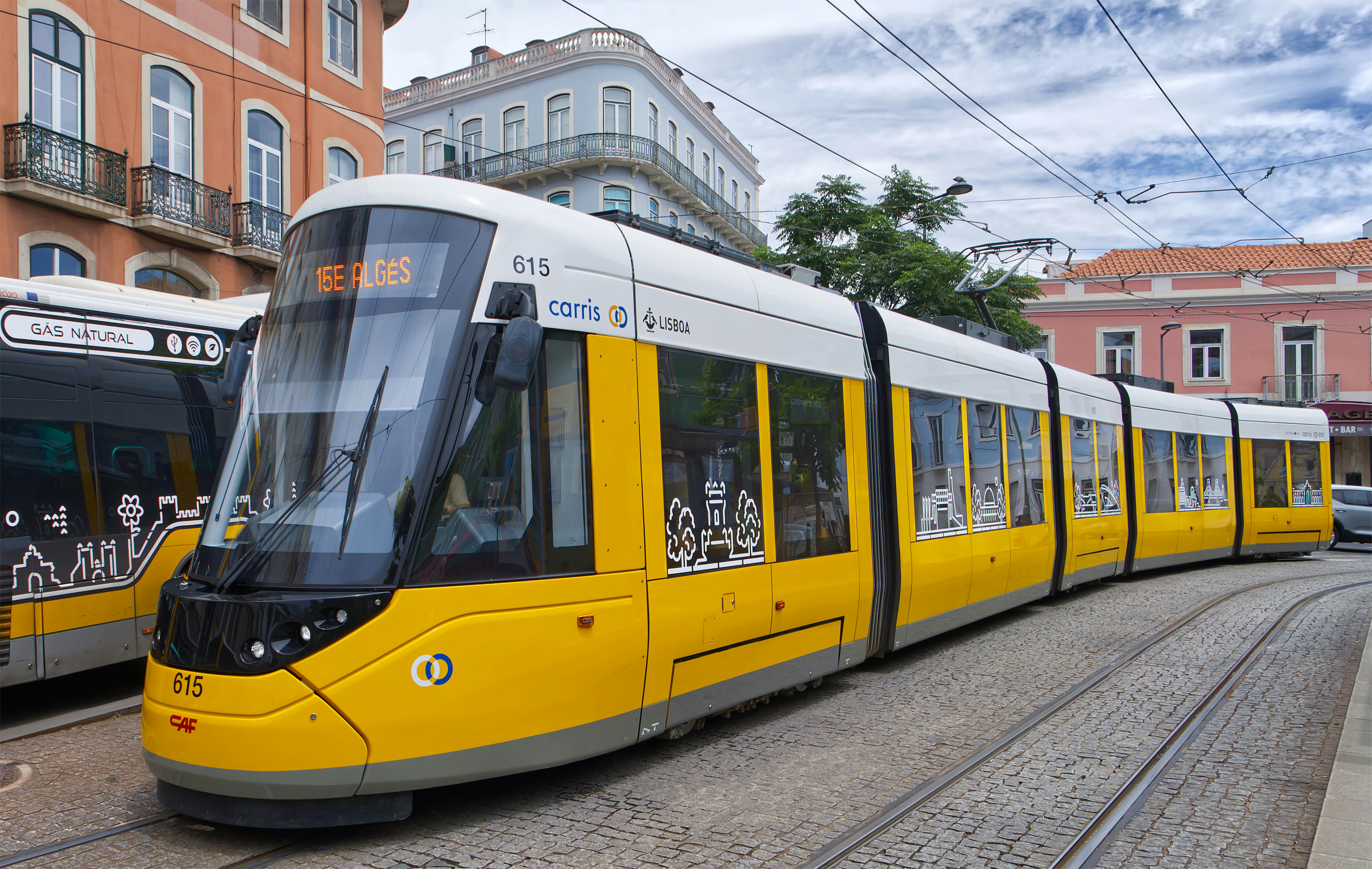 A yellow and white tram on cobblestone tracks in Lisbon, Portugal