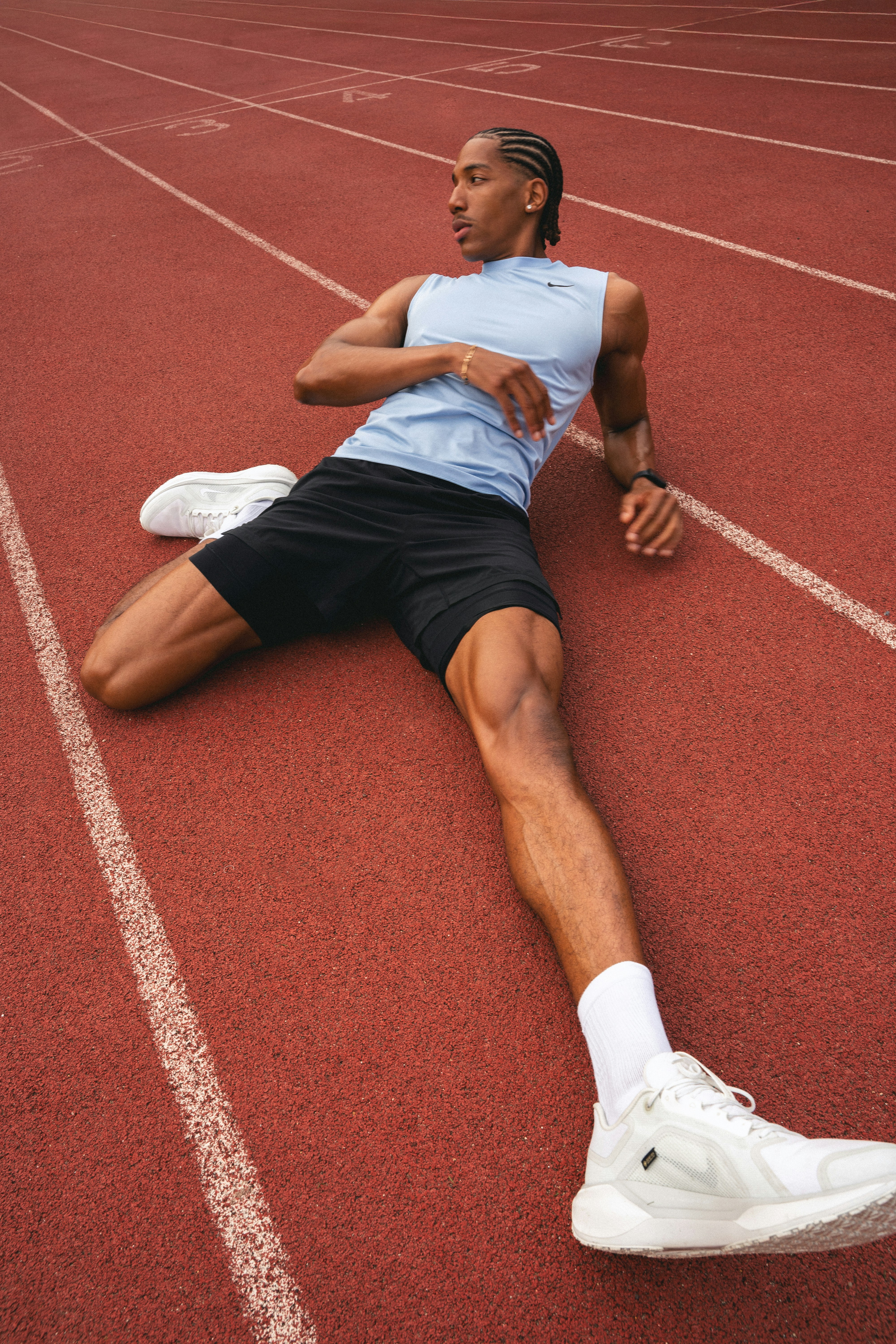 A runner stretching on a red running track