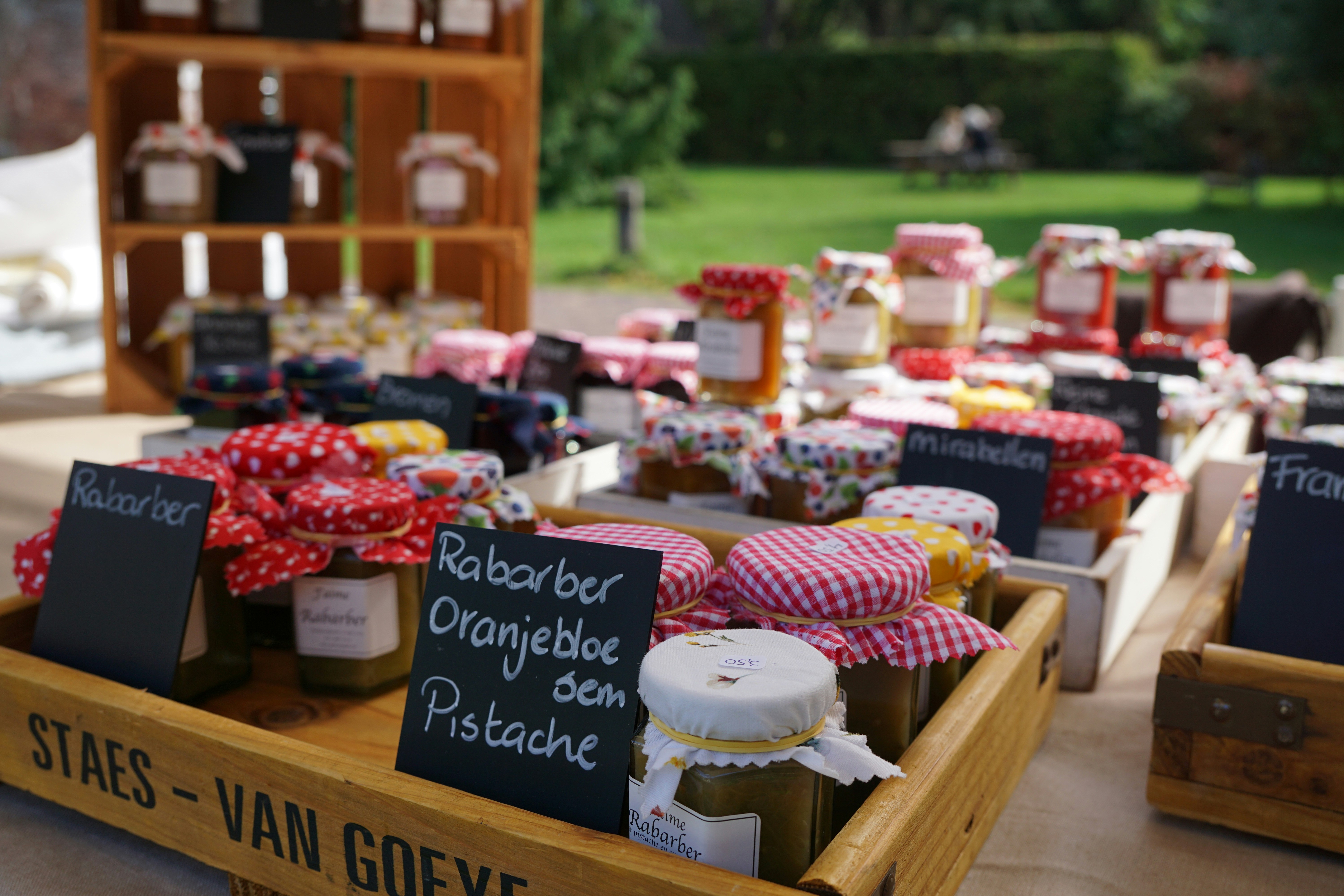 Glass jars of jam with patterned fabric lids in wooden crates at a market