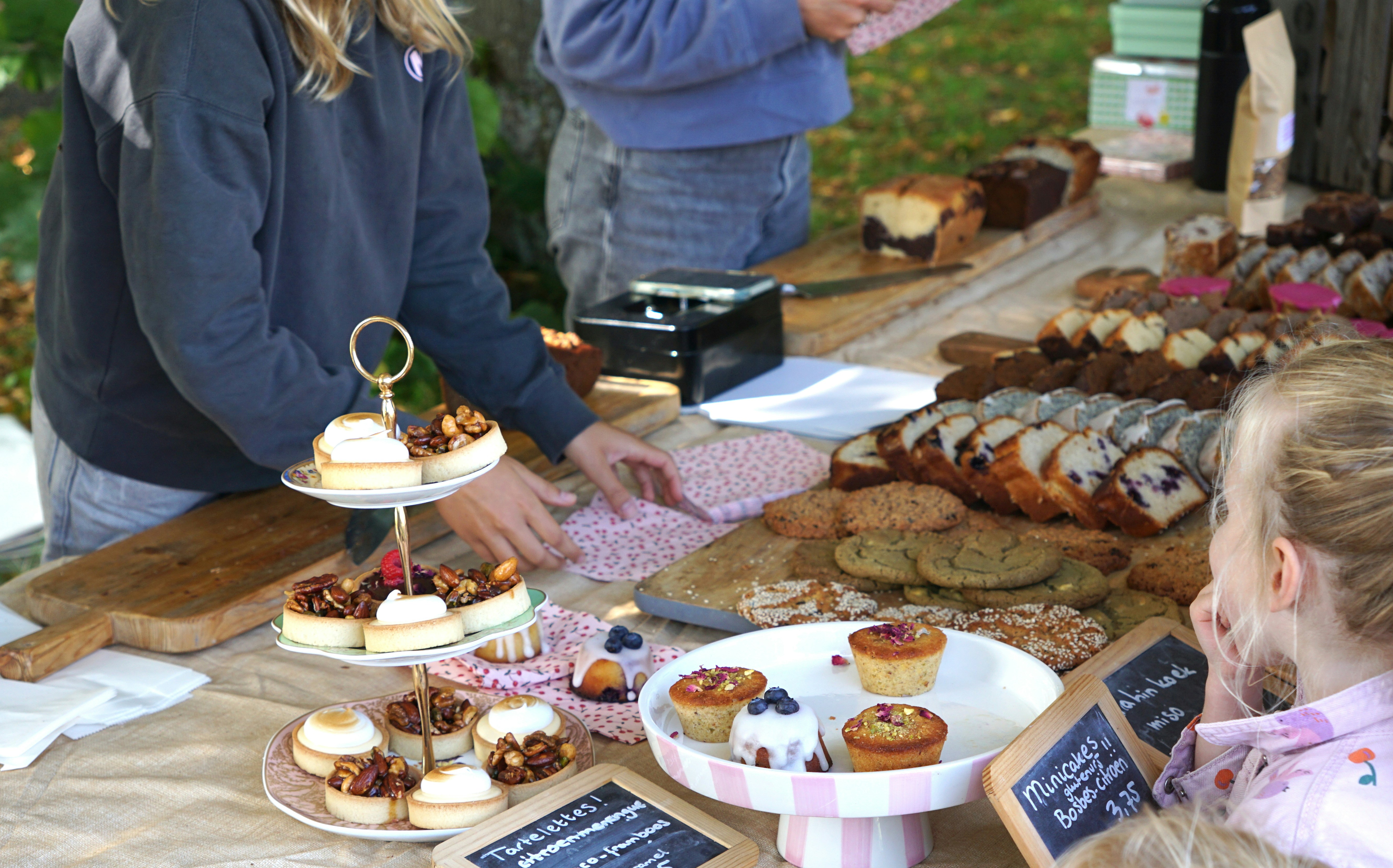 A child looking at a table of assorted pastries and cakes at a market