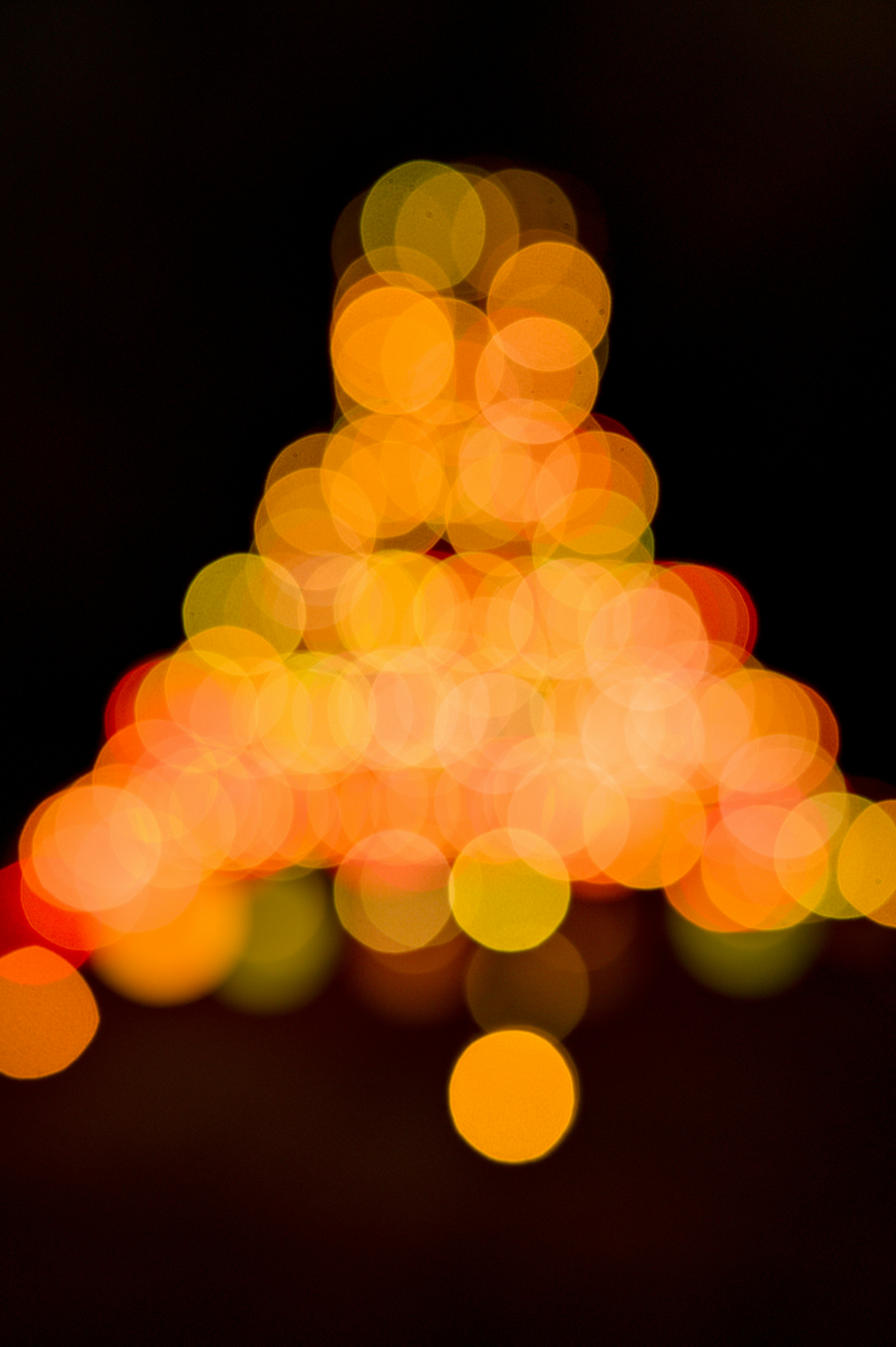 A triangular arrangement of glowing orange and yellow bokeh circles against a black background