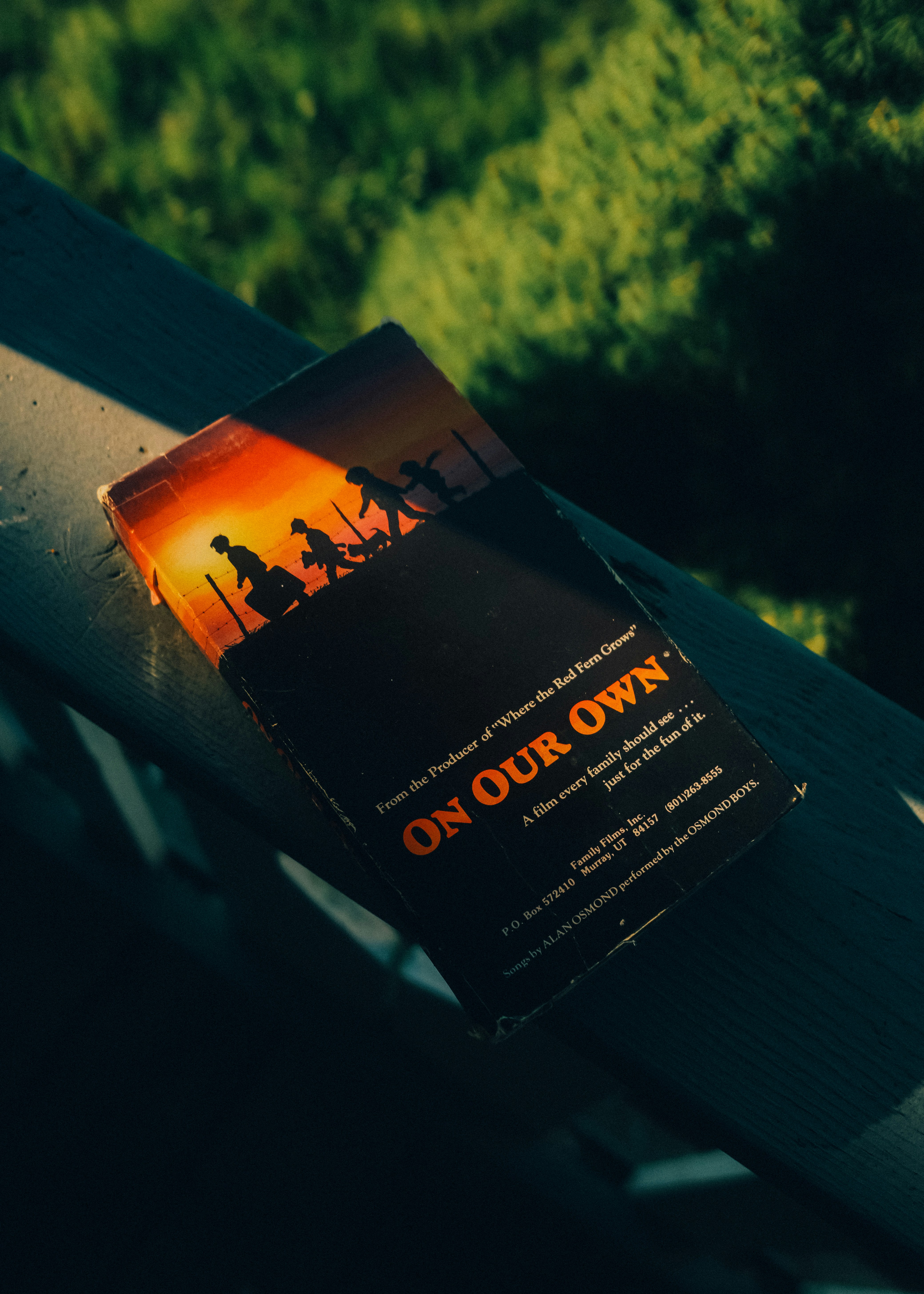A vintage VHS tape titled On Our Own resting on a wooden railing