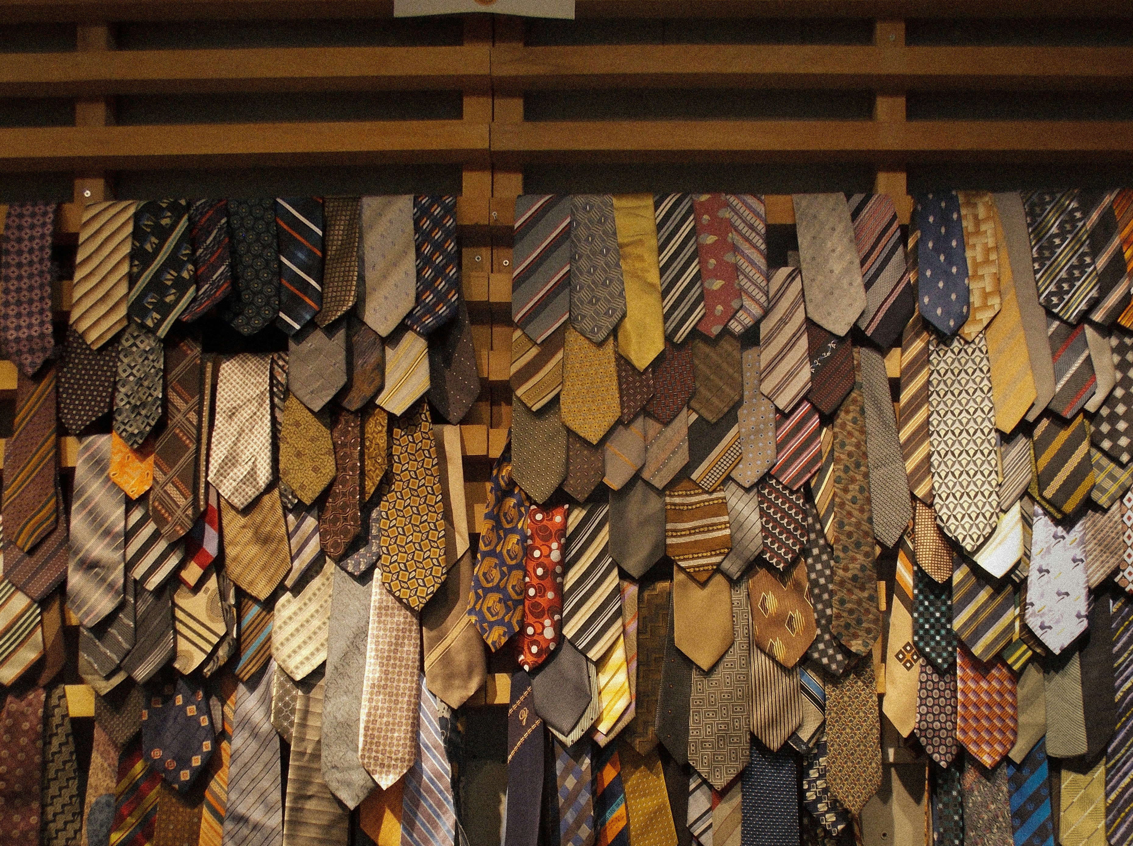 A large collection of neckties in various patterns and colors hanging on a rack