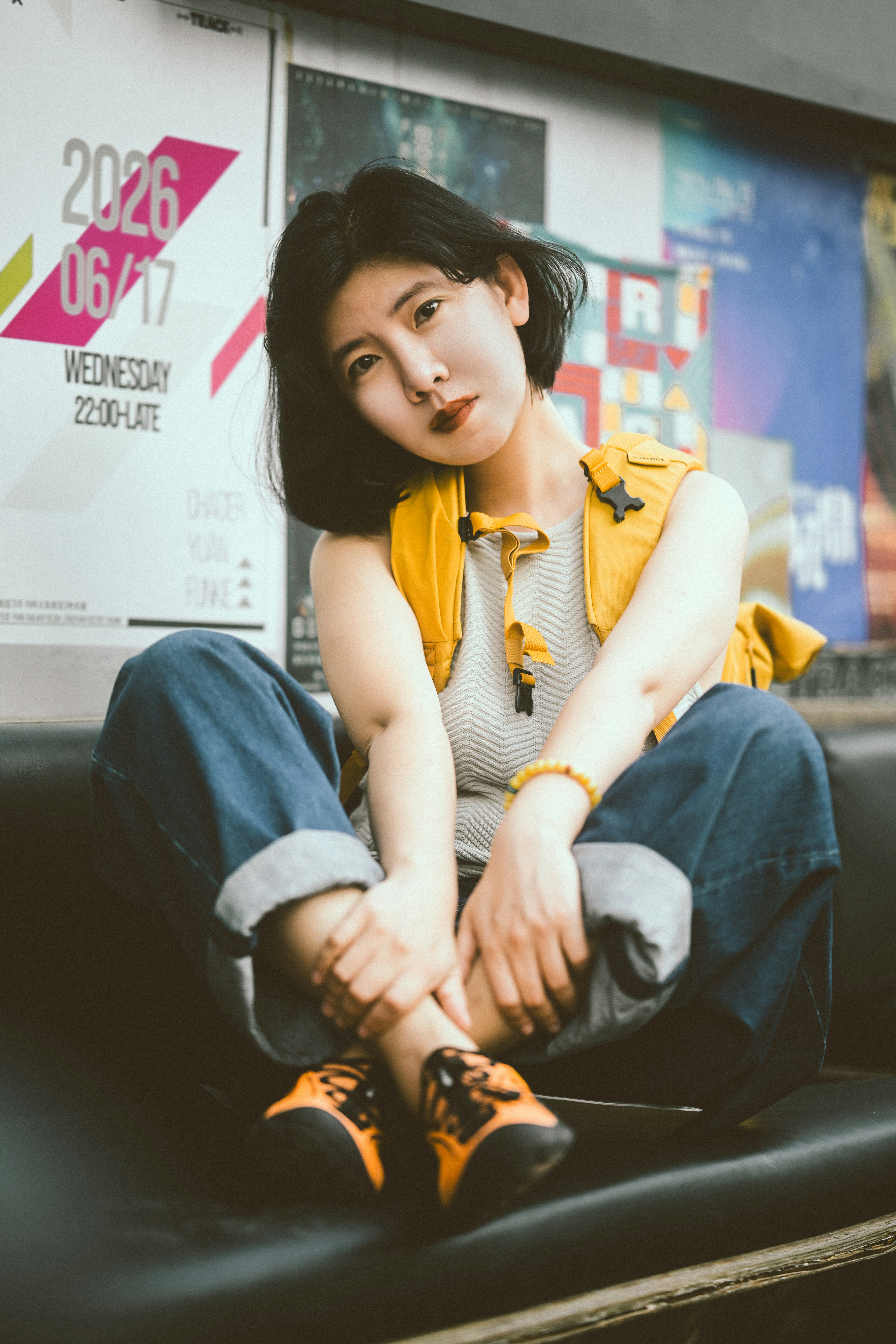 A woman with short dark hair wearing a yellow backpack and blue jeans