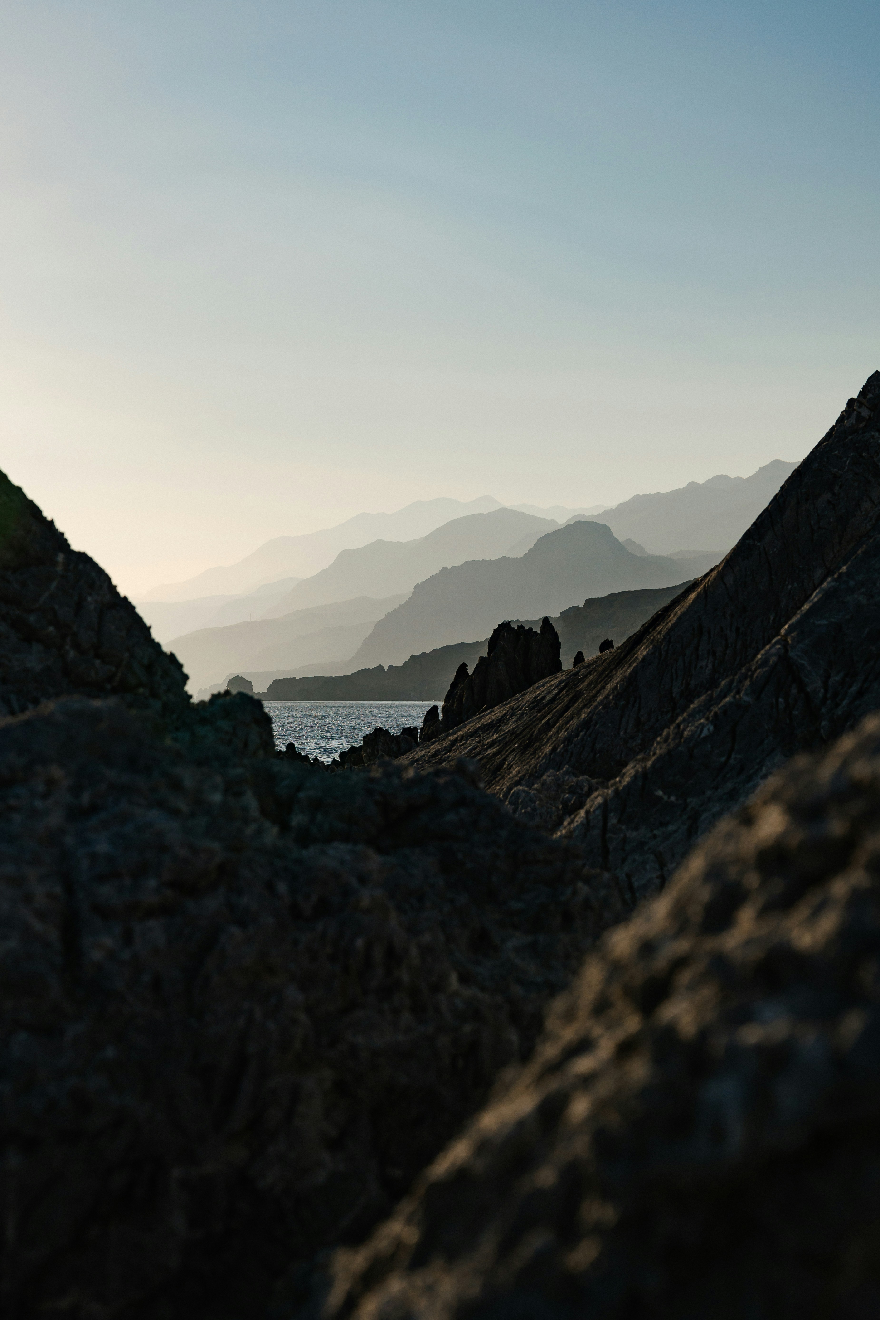 Jagged dark rocks framing a distant view of hazy mountains and the sea