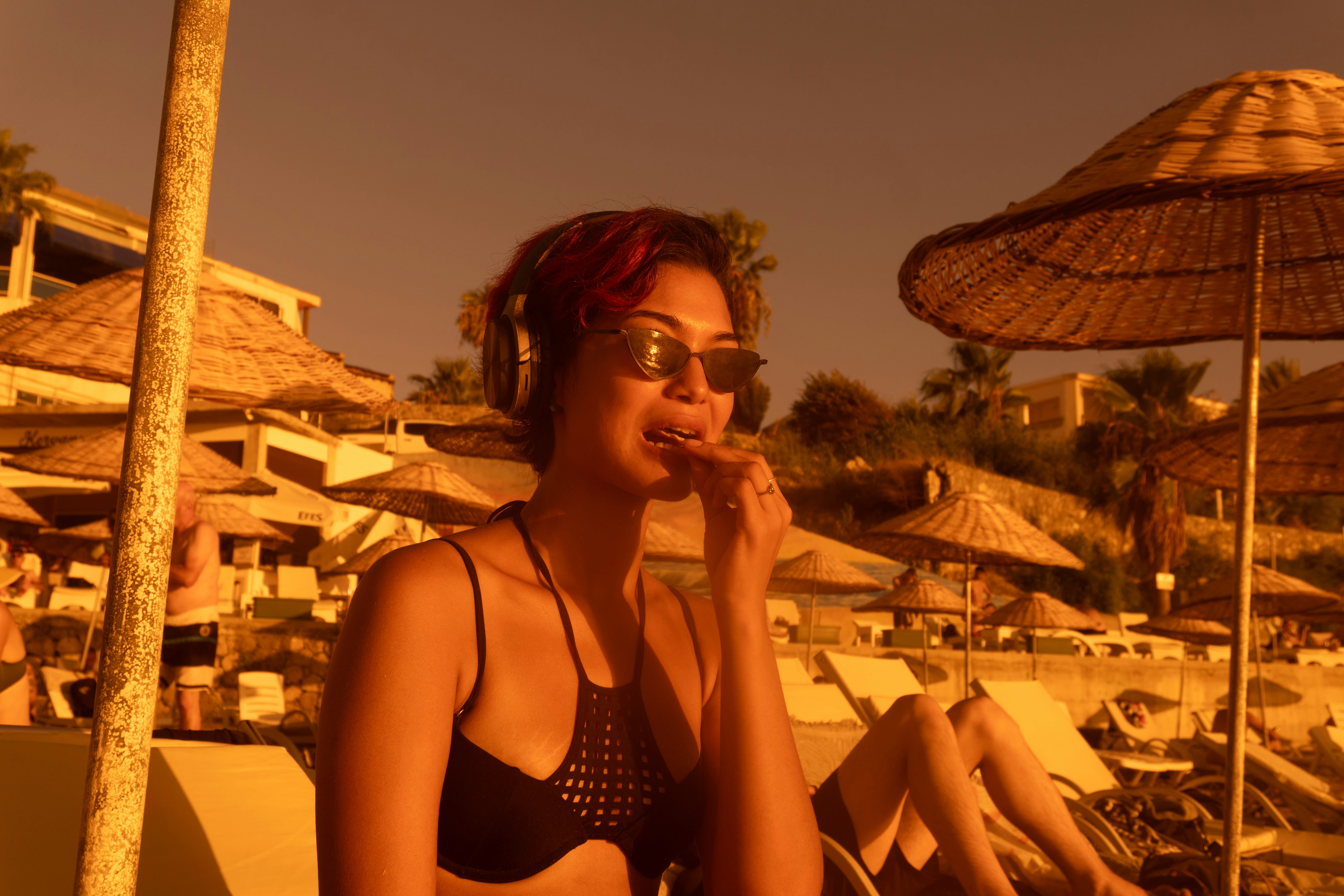Una donna in bikini nero e occhiali da sole che mangia su una spiaggia all'ora dorata