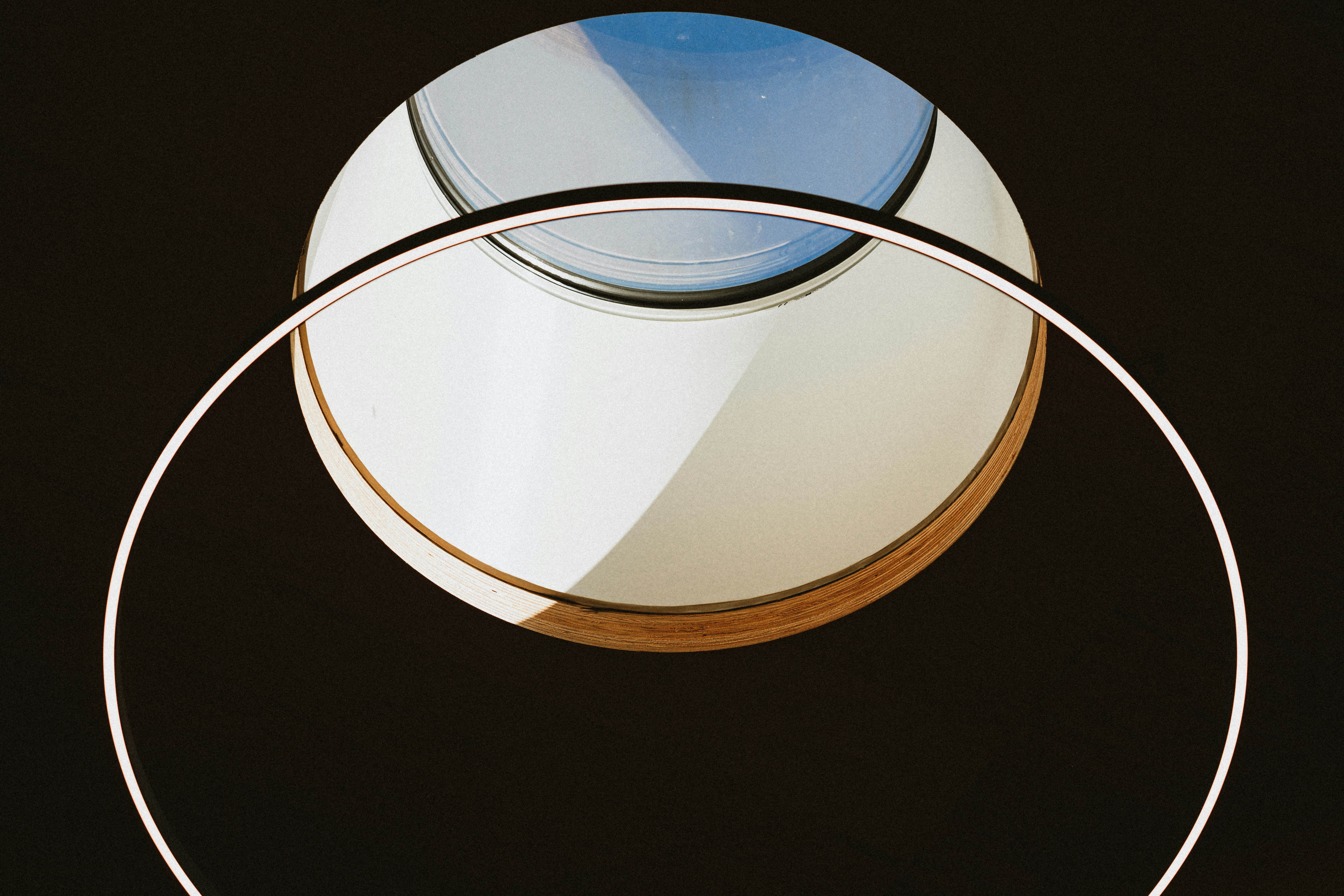 A circular light fixture with a wooden rim against a dark background