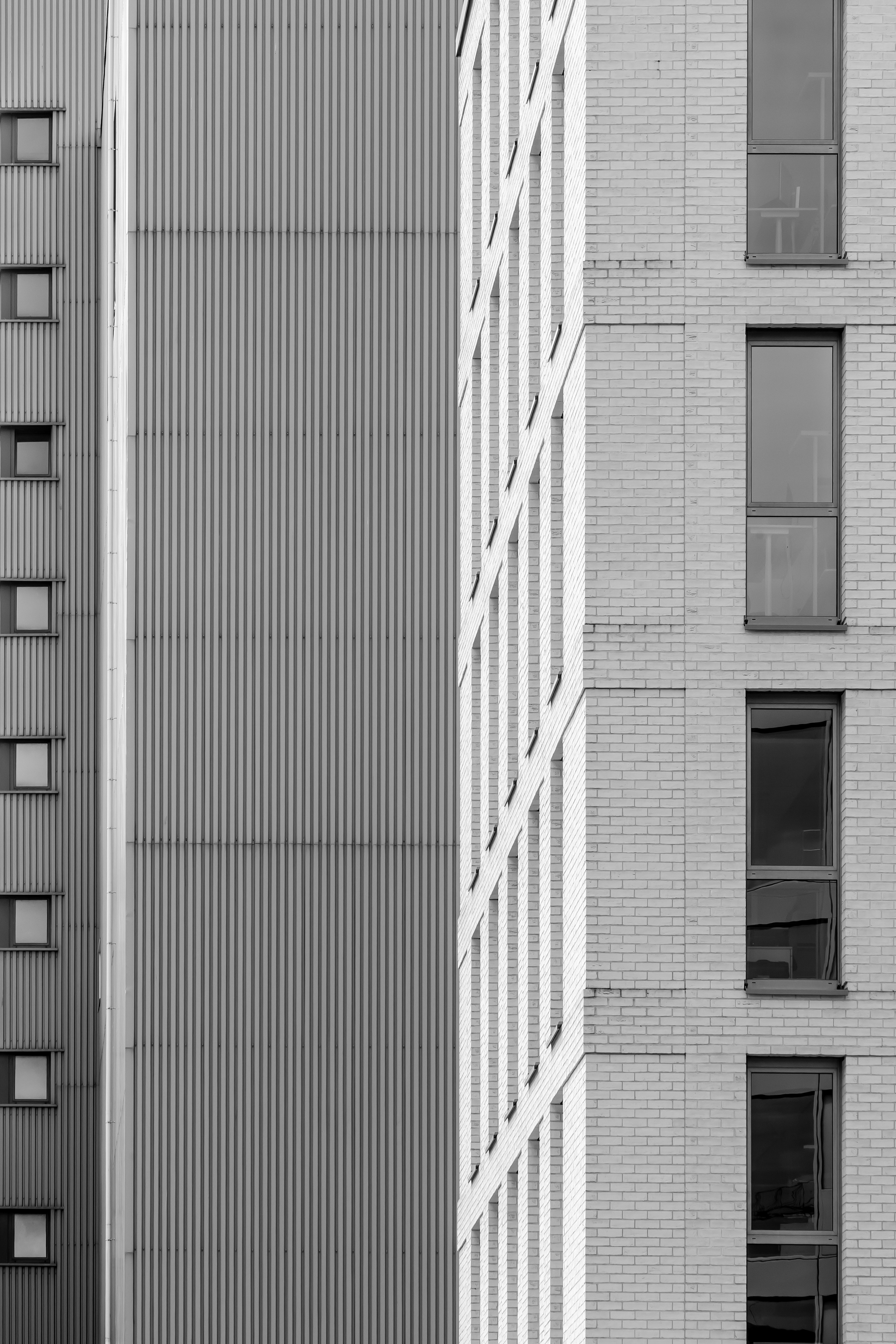 Une vue en noir et blanc d’un mur en tôle ondulée à côté d’un bâtiment en briques