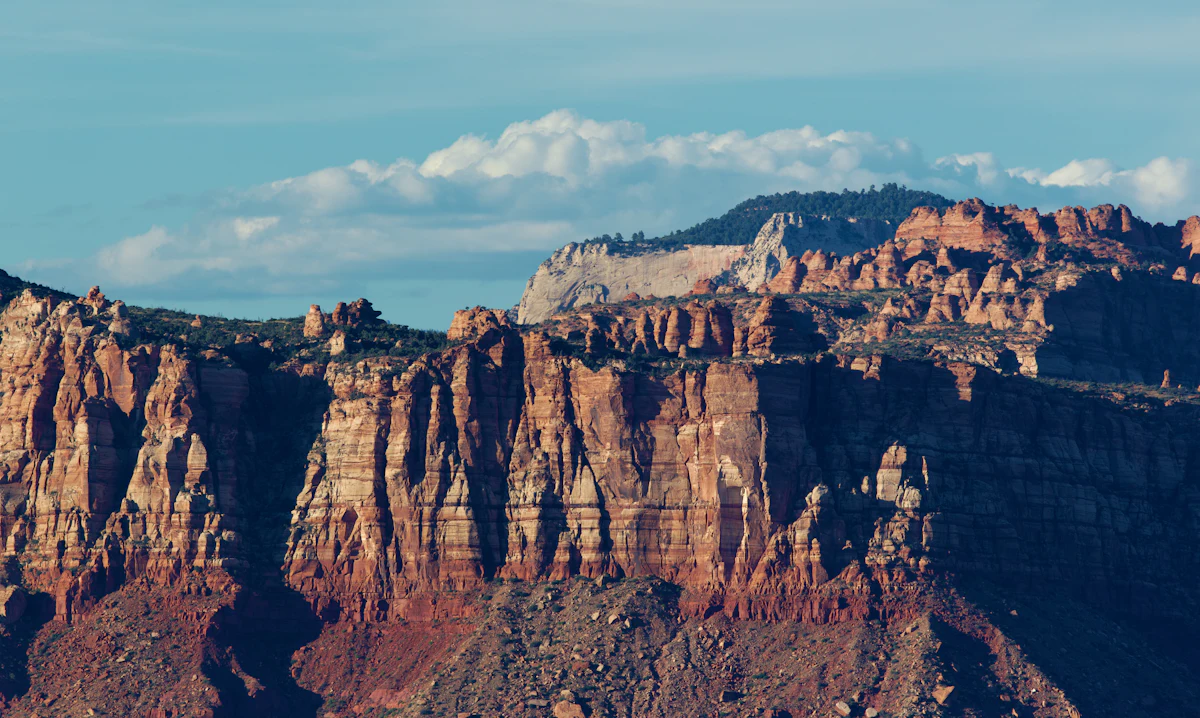 Layered red sandstone cliffs and a white dome toward Zion National Park, seen from the edge of Gooseberry Mesa