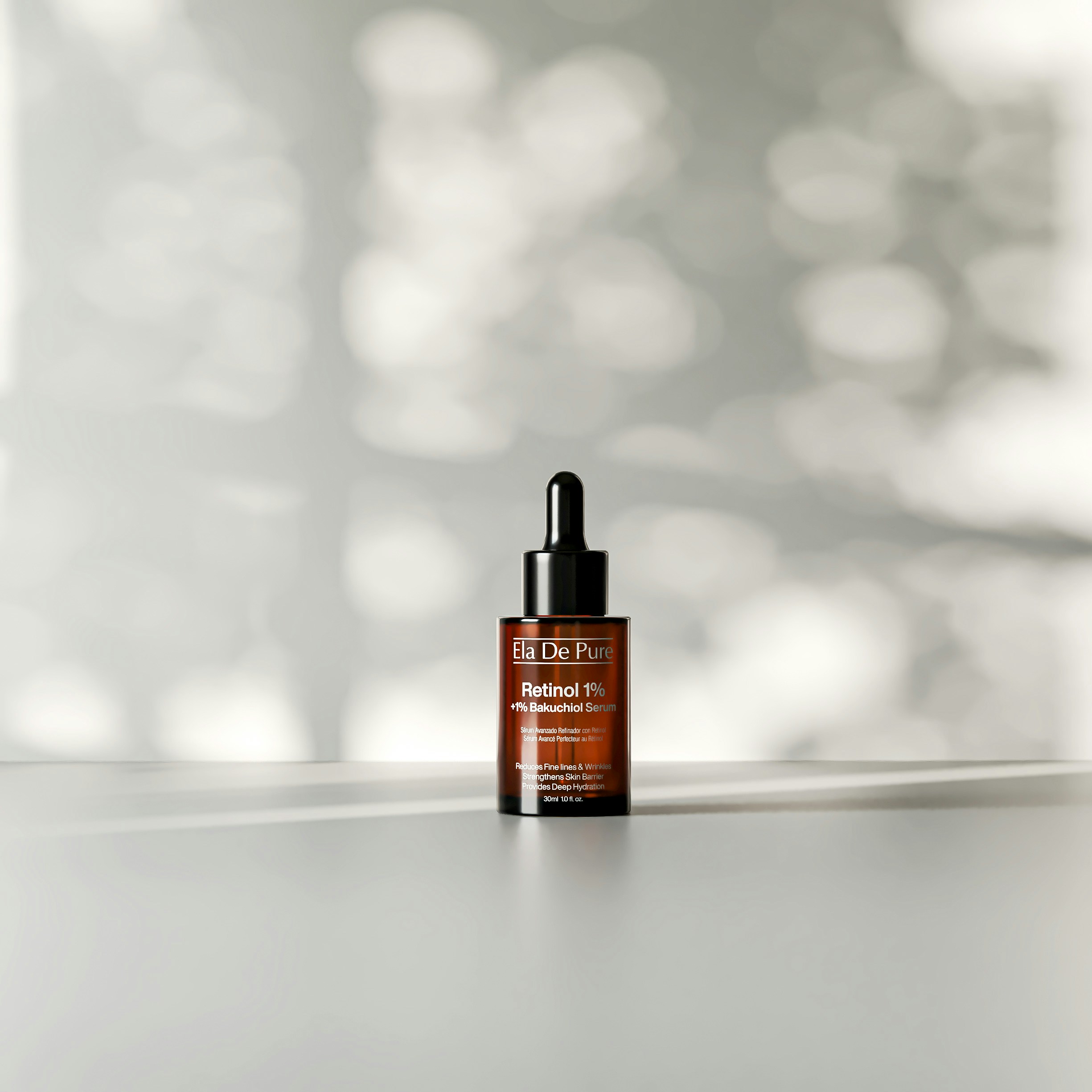 A brown glass dropper bottle of retinol serum on a white surface with dappled light