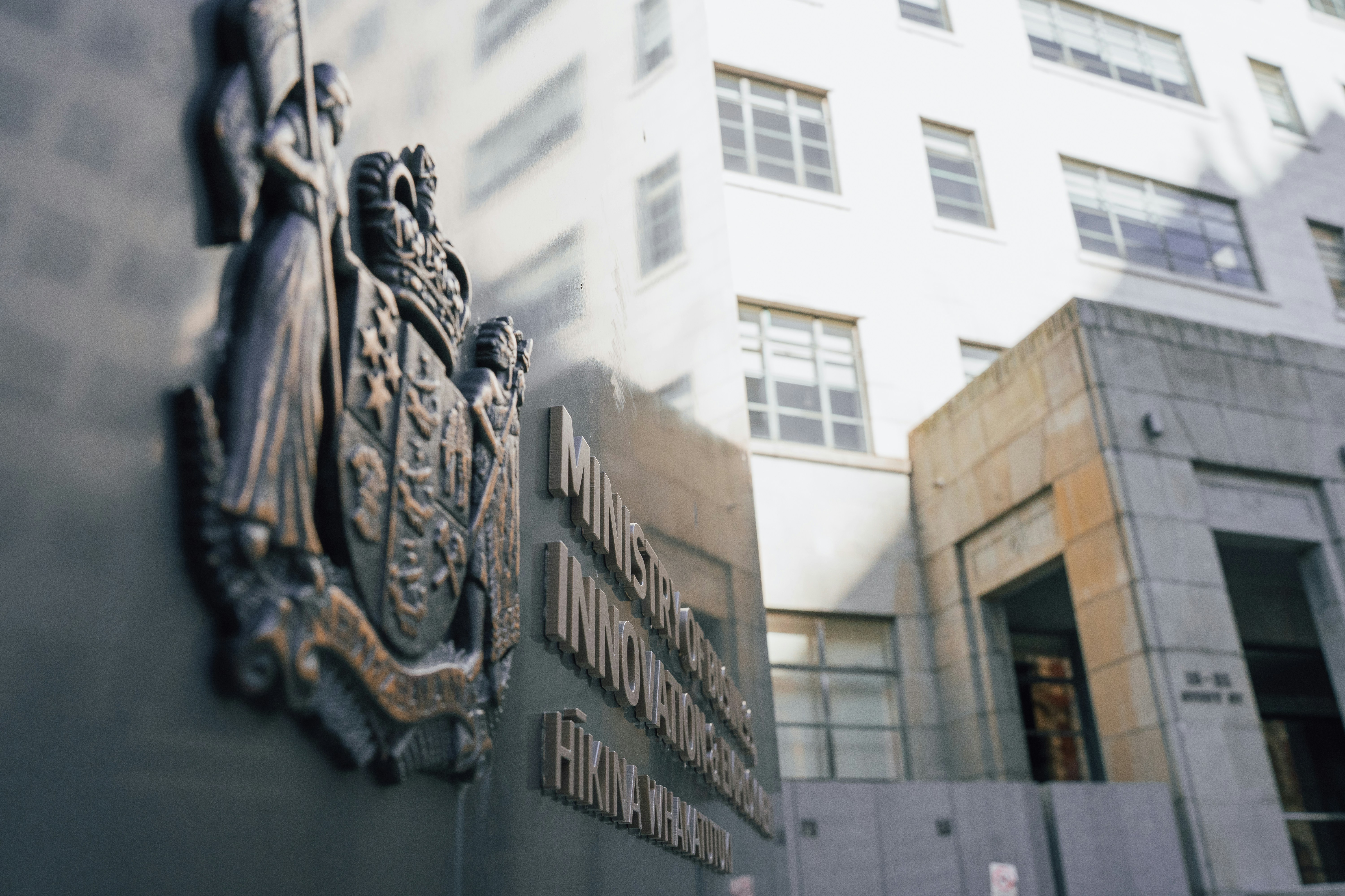 A bronze coat of arms and raised lettering on a dark building exterior