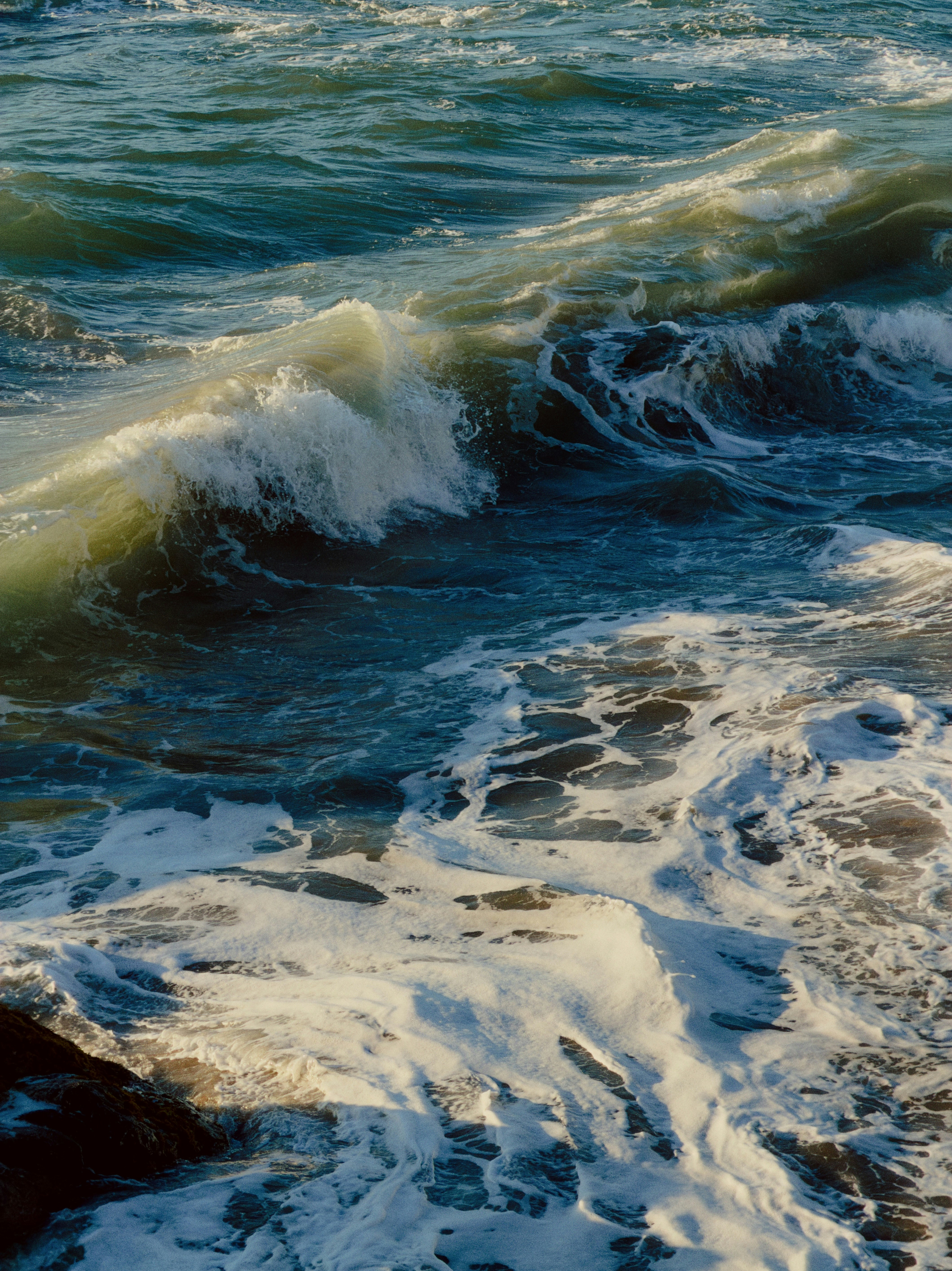 Une vague de mer déferlante avec de la mousse blanche sur une eau bleu foncé