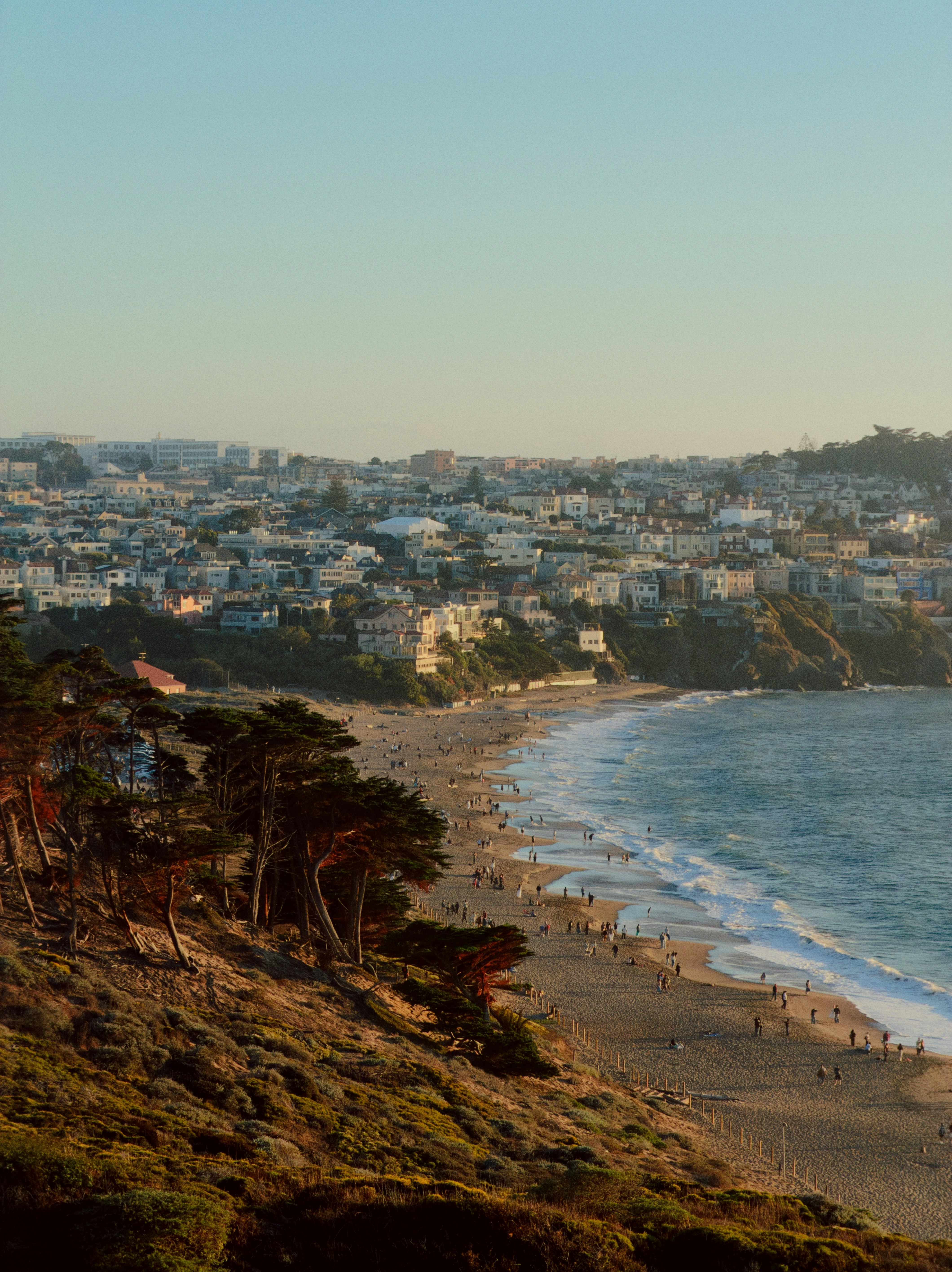 Des gens sur une plage de sable en contrebas d’une colline avec des maisons à San Francisco