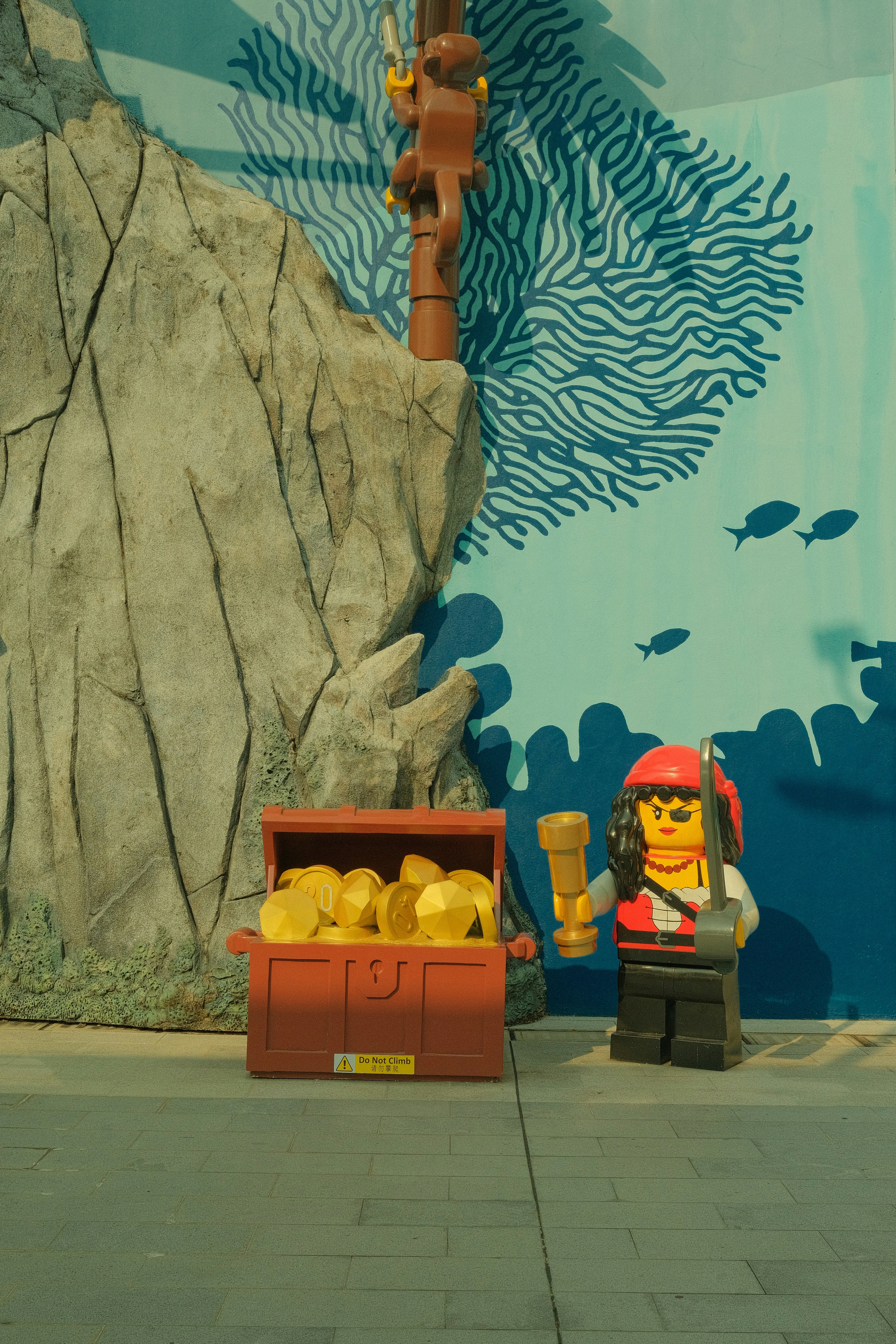 Une figurine de pirate Lego avec un coffre au trésor rempli de pièces d’or près d’un rocher