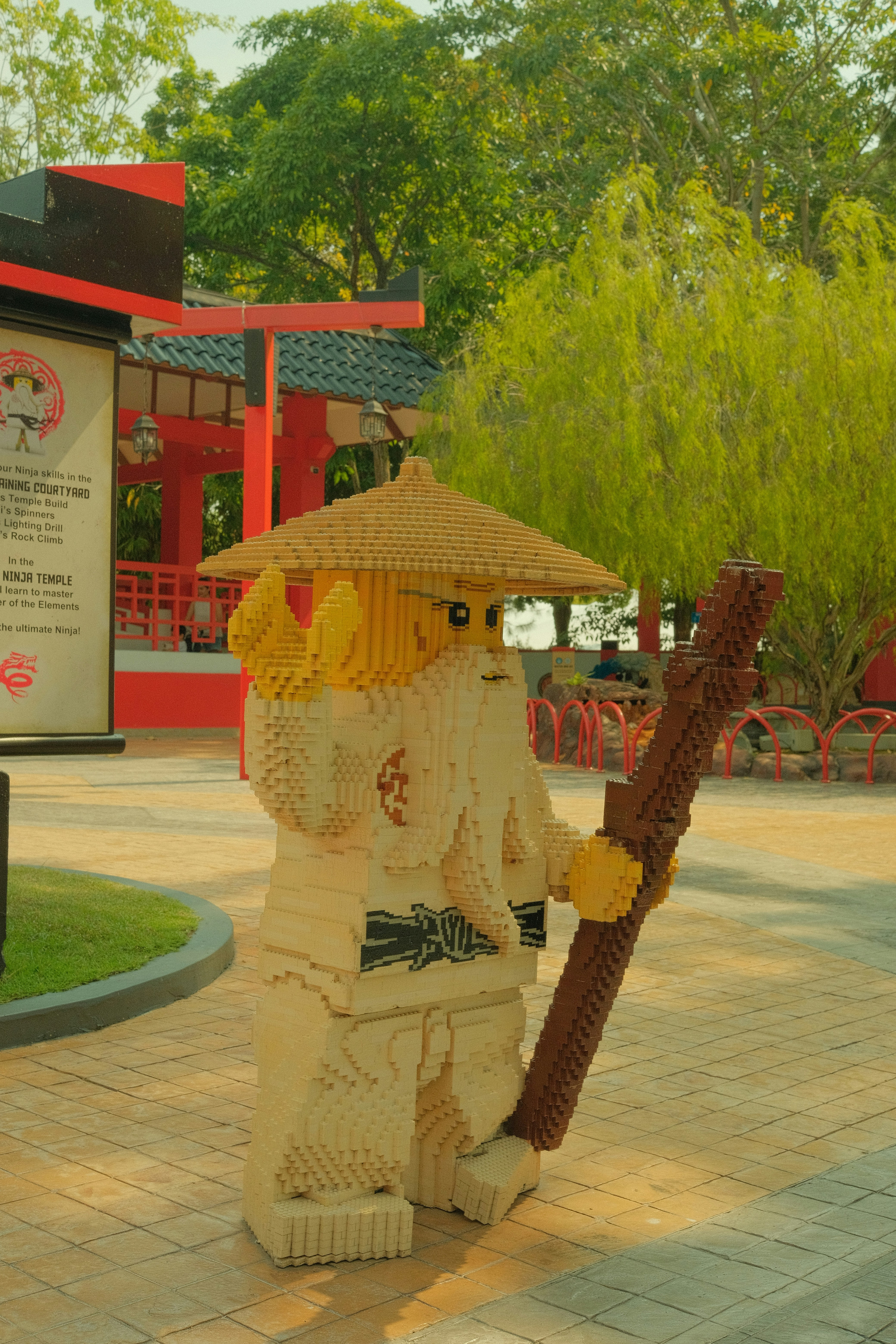 Une grande figurine Lego d’un vieil homme avec un bâton dans un parc