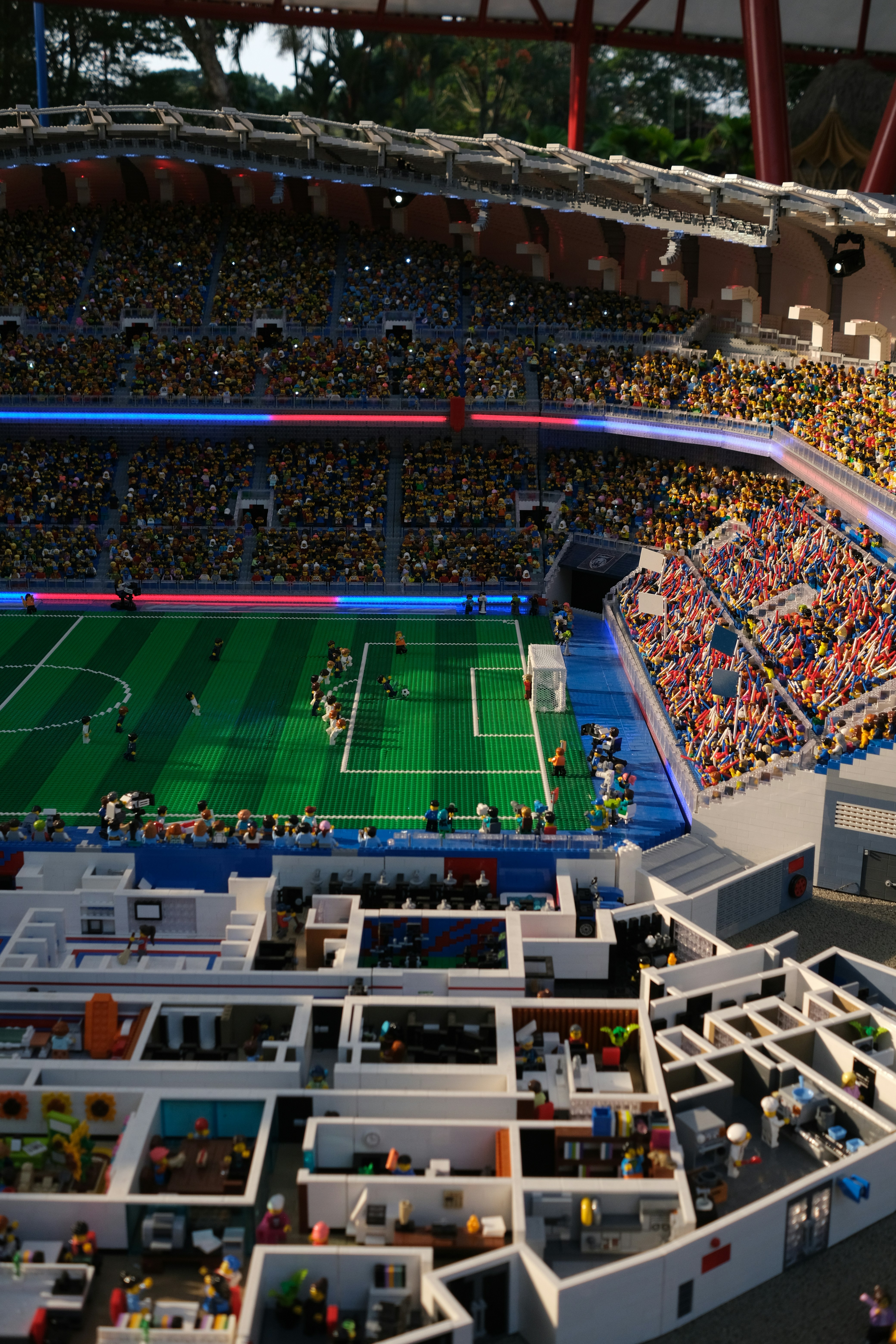 Un mini-stade construit en briques plastiques avec un match de football et des salles intérieures