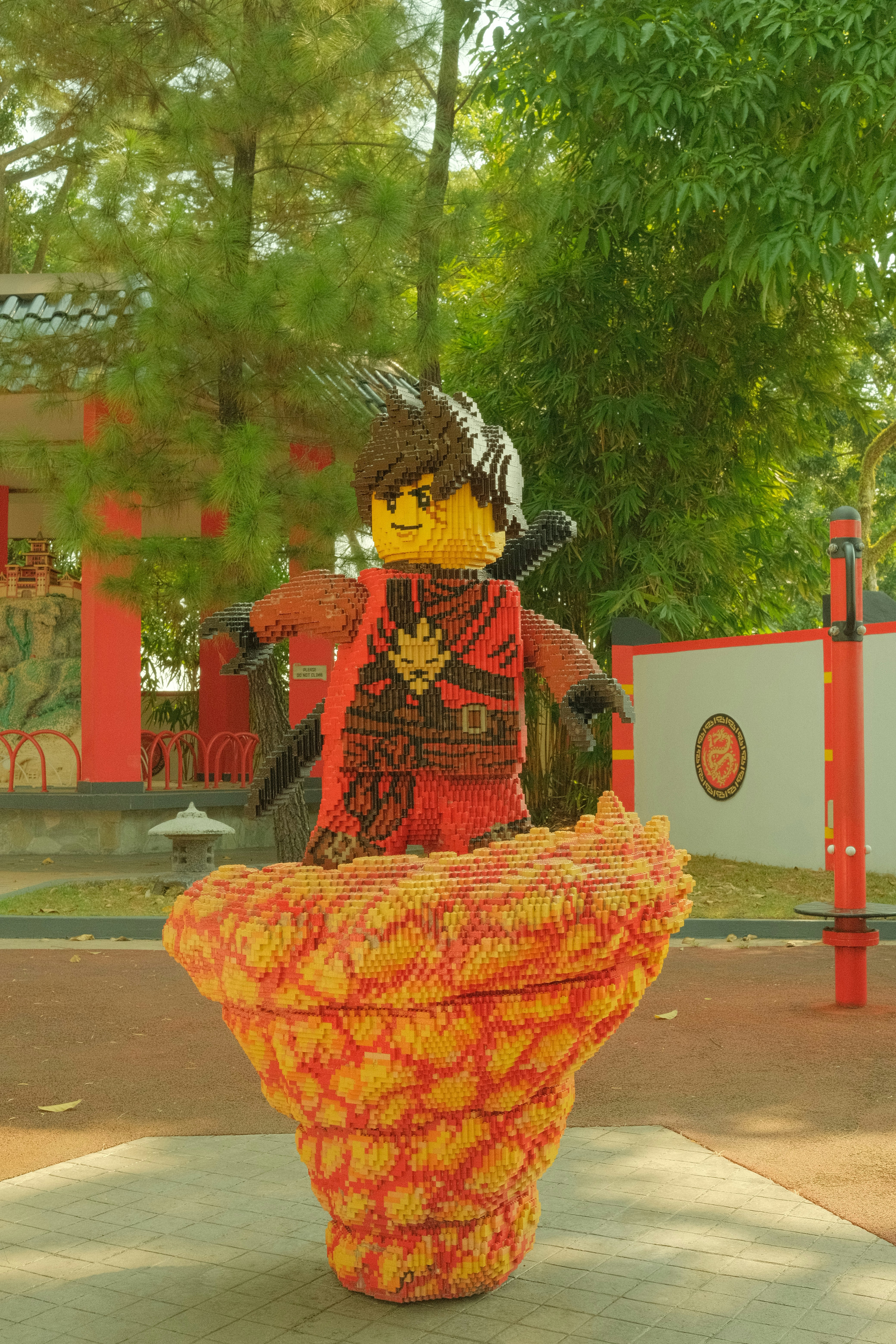 Une grande sculpture Lego représentant un personnage ninja debout sur une base de feu tourbillonnante