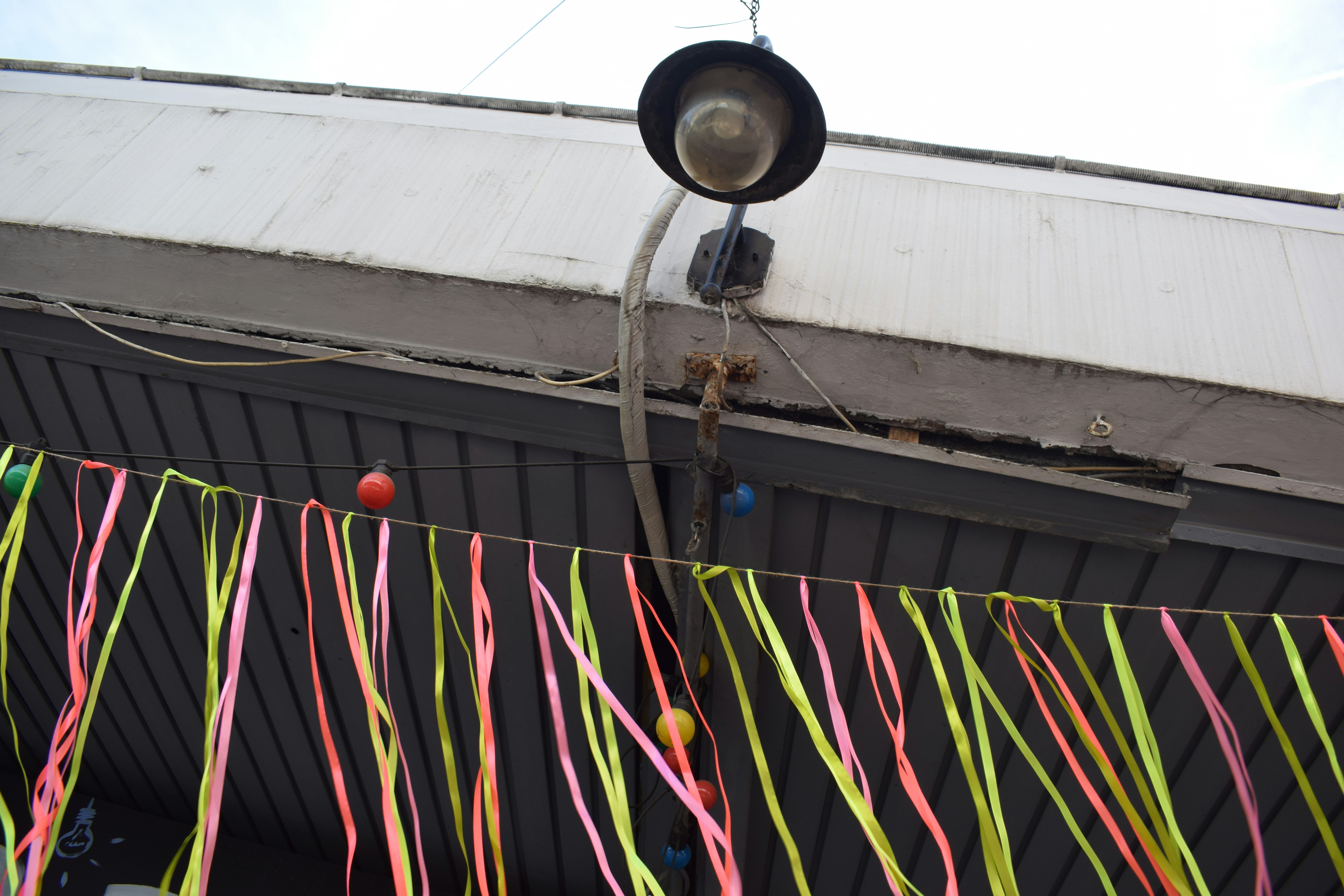 A string of colorful ribbons hanging below a street lamp on a building