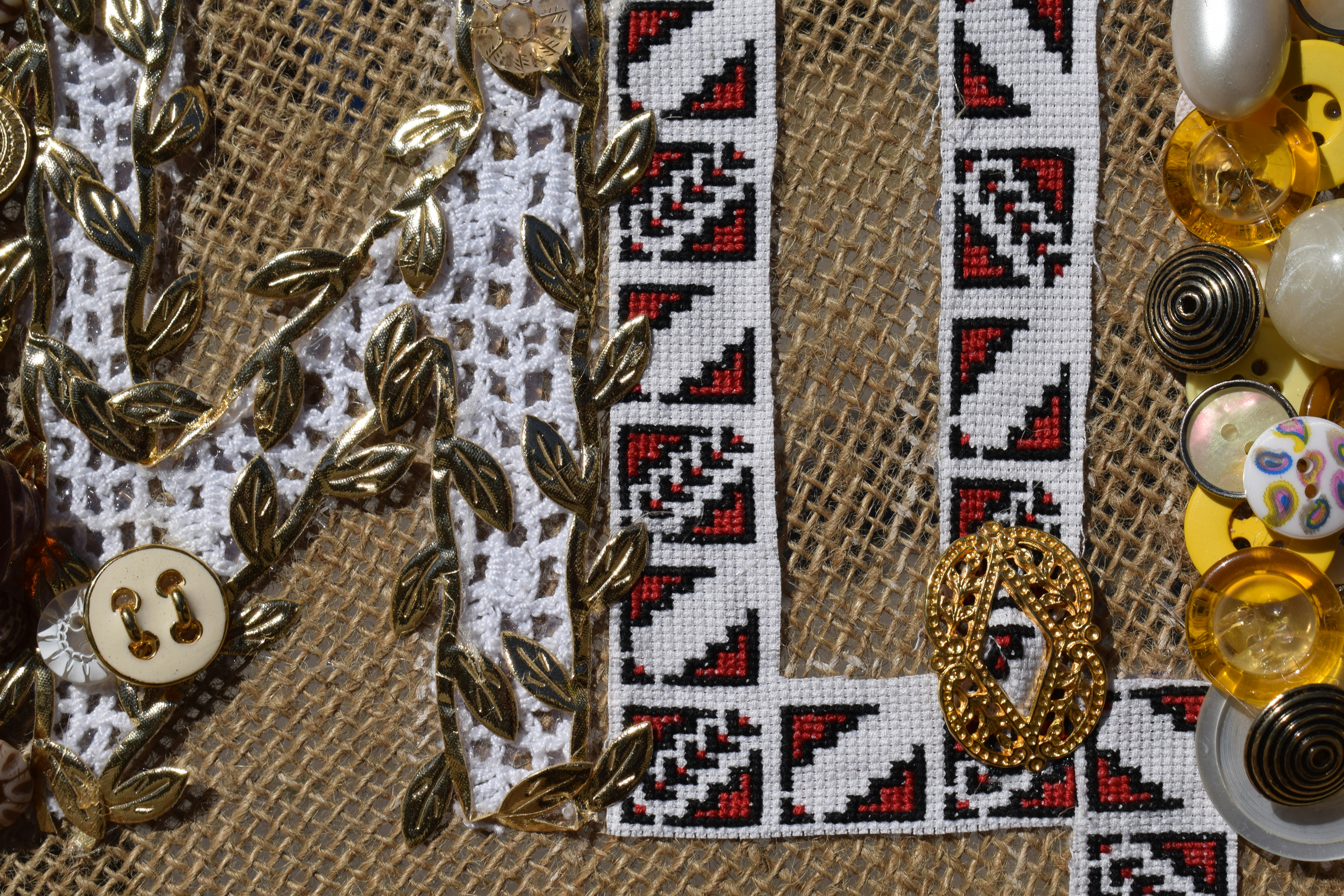 Burlap fabric decorated with white lace, red and black embroidery, and gold leaf accents