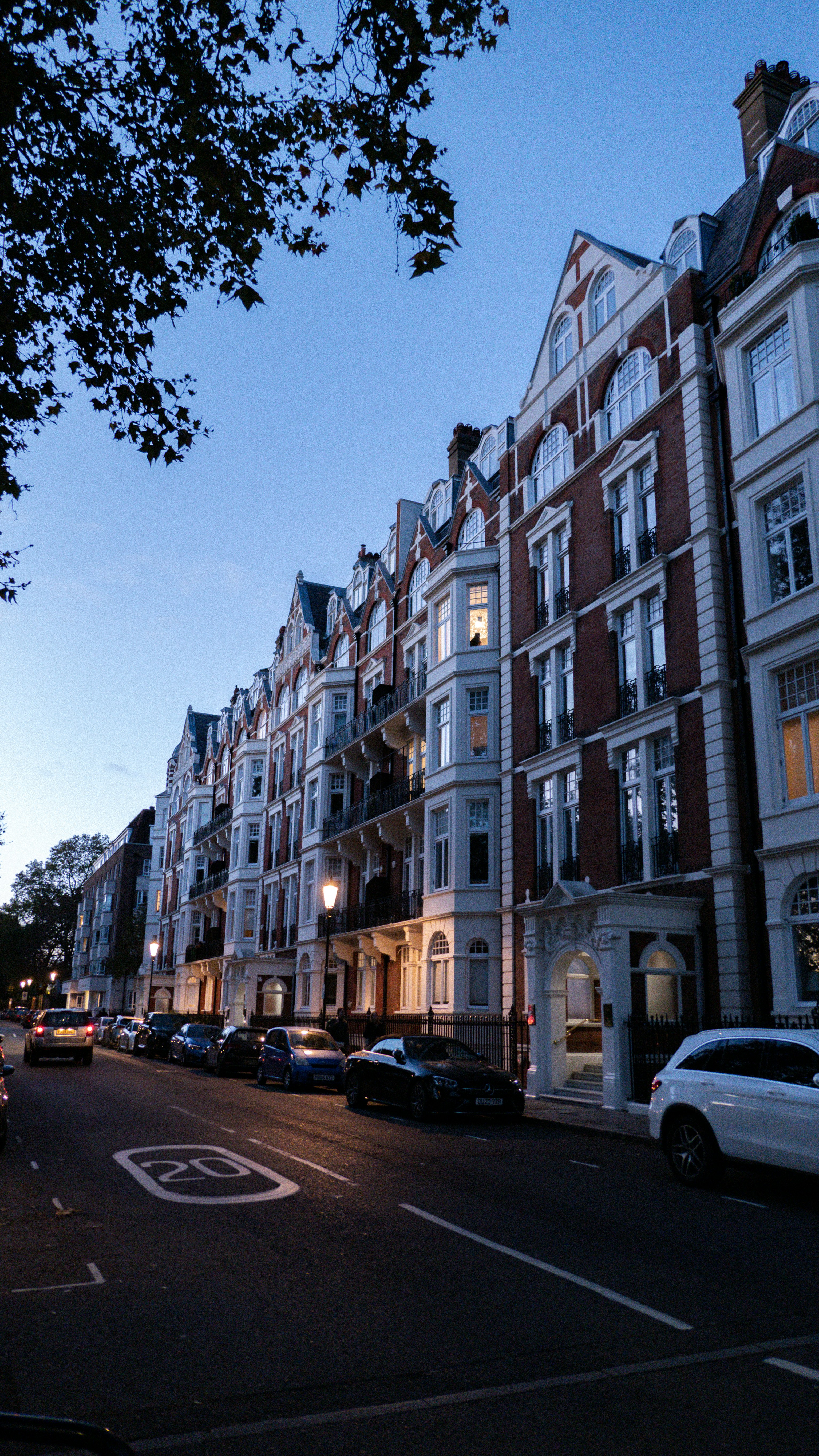 A row of red brick townhouses with white trim along a city street