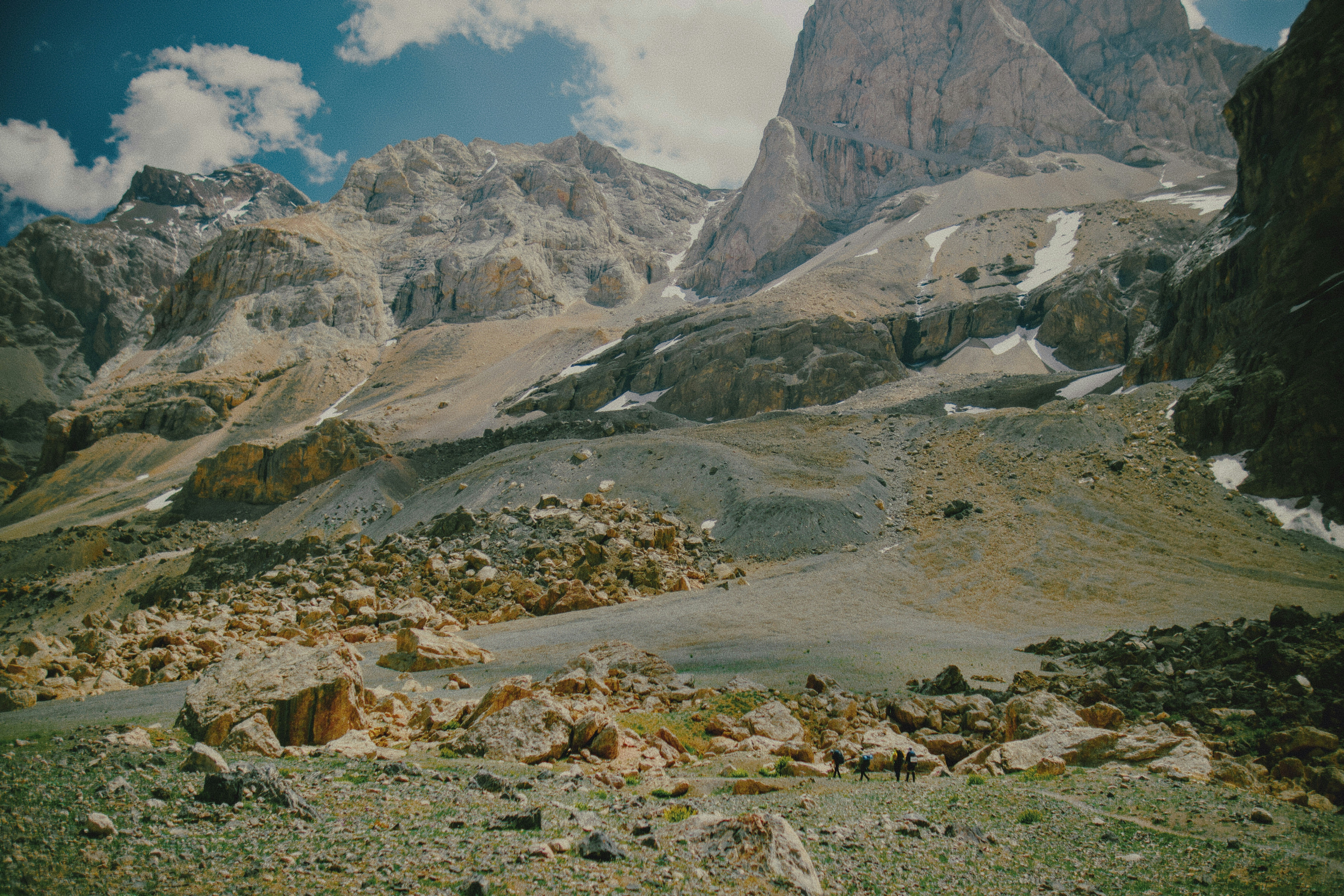 Eine Gruppe von Menschen, die durch eine felsige Berglandschaft mit Schneeflecken wandert