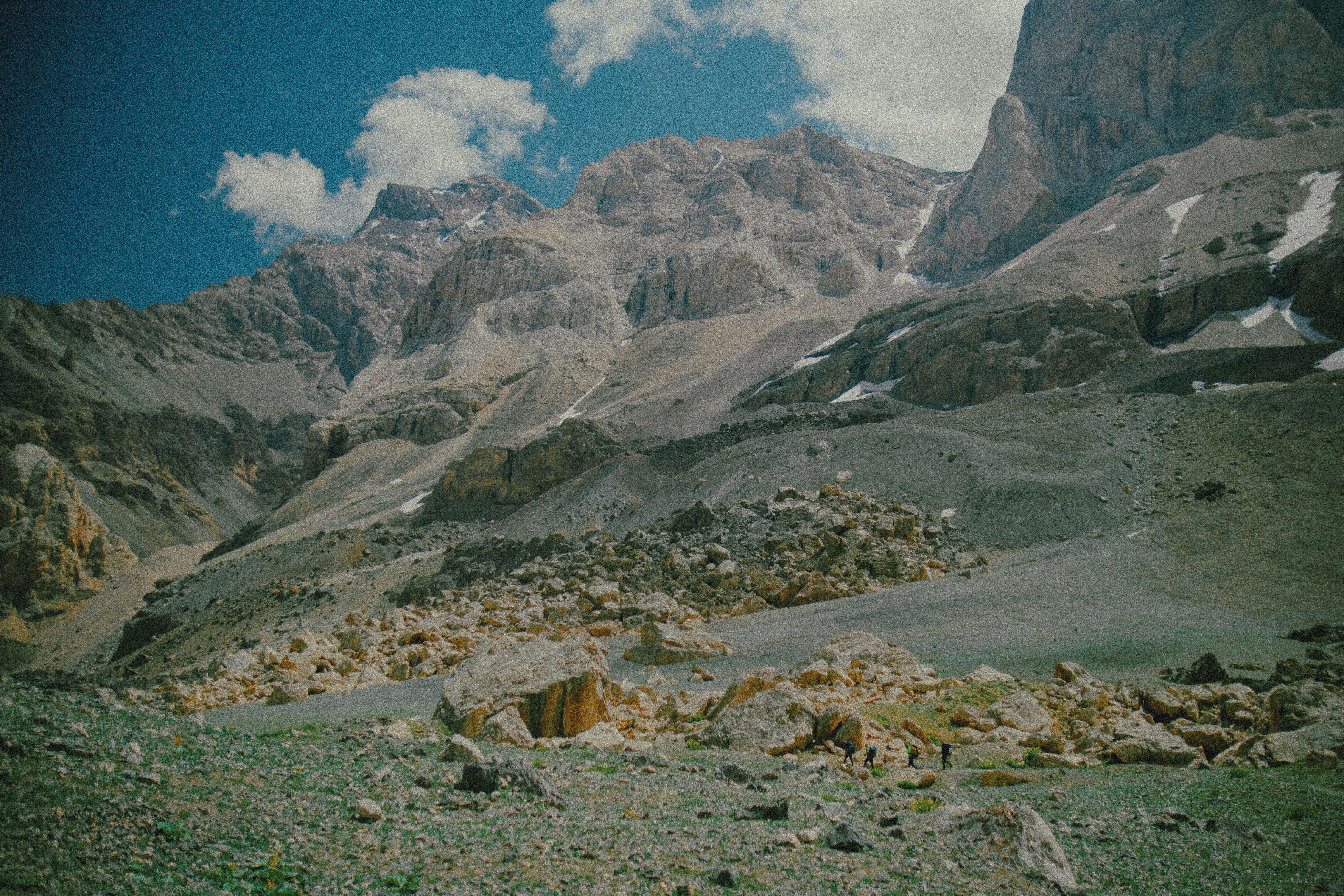 Eine Gruppe von Menschen, die unter blauem Himmel über eine felsige Berglandschaft wandert