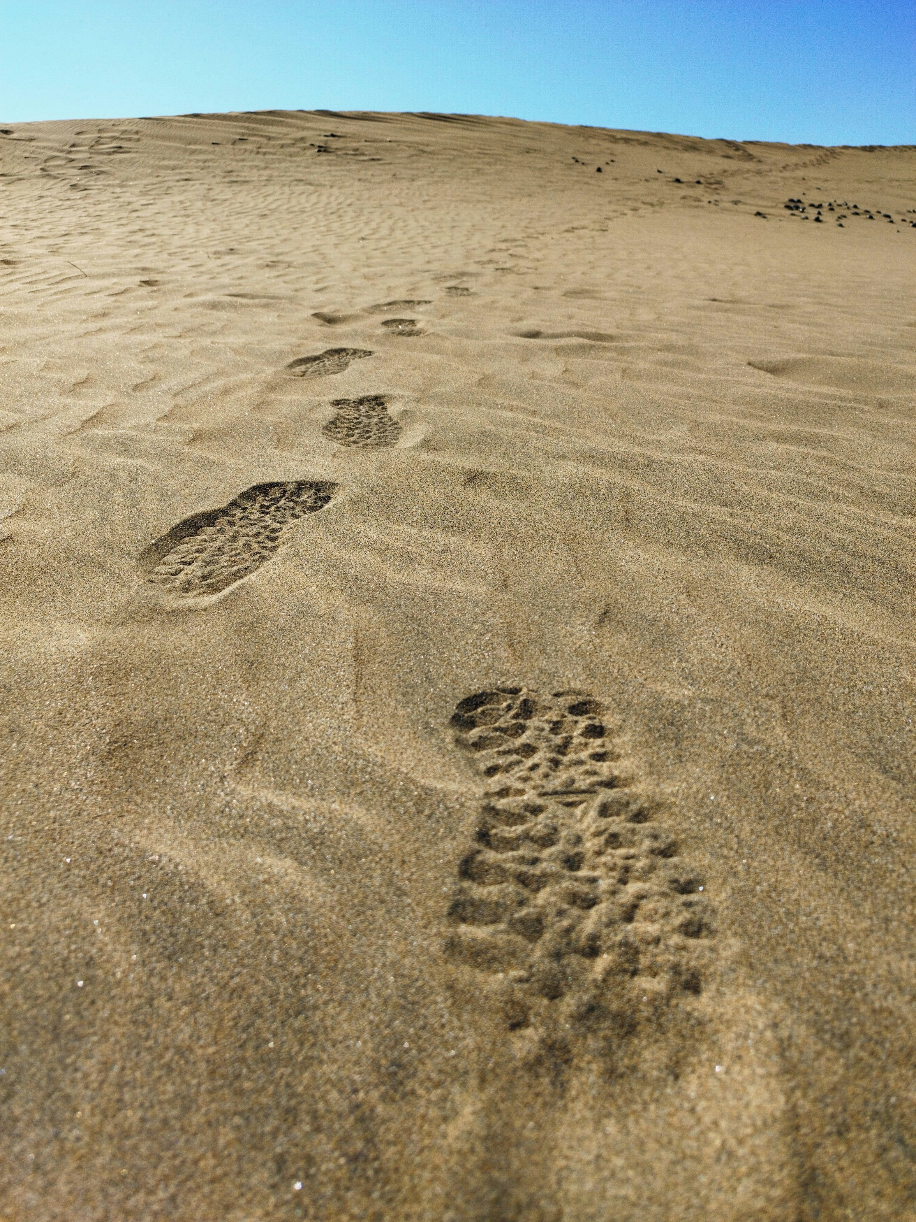 Des empreintes d’une botte dans le sable d’une dune du désert