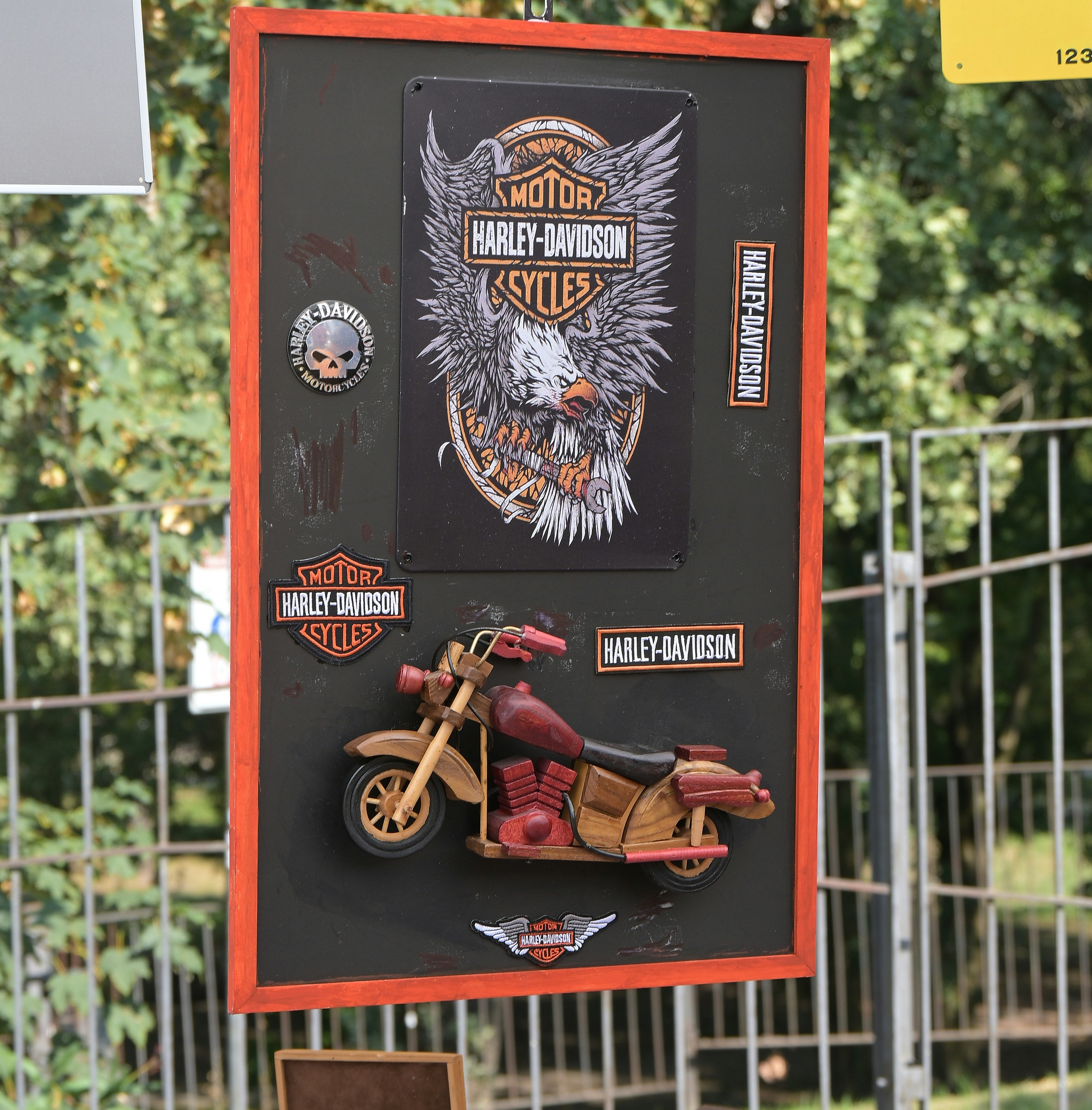 Um modelo de motocicleta de madeira e patches Harley-Davidson montados em um painel preto