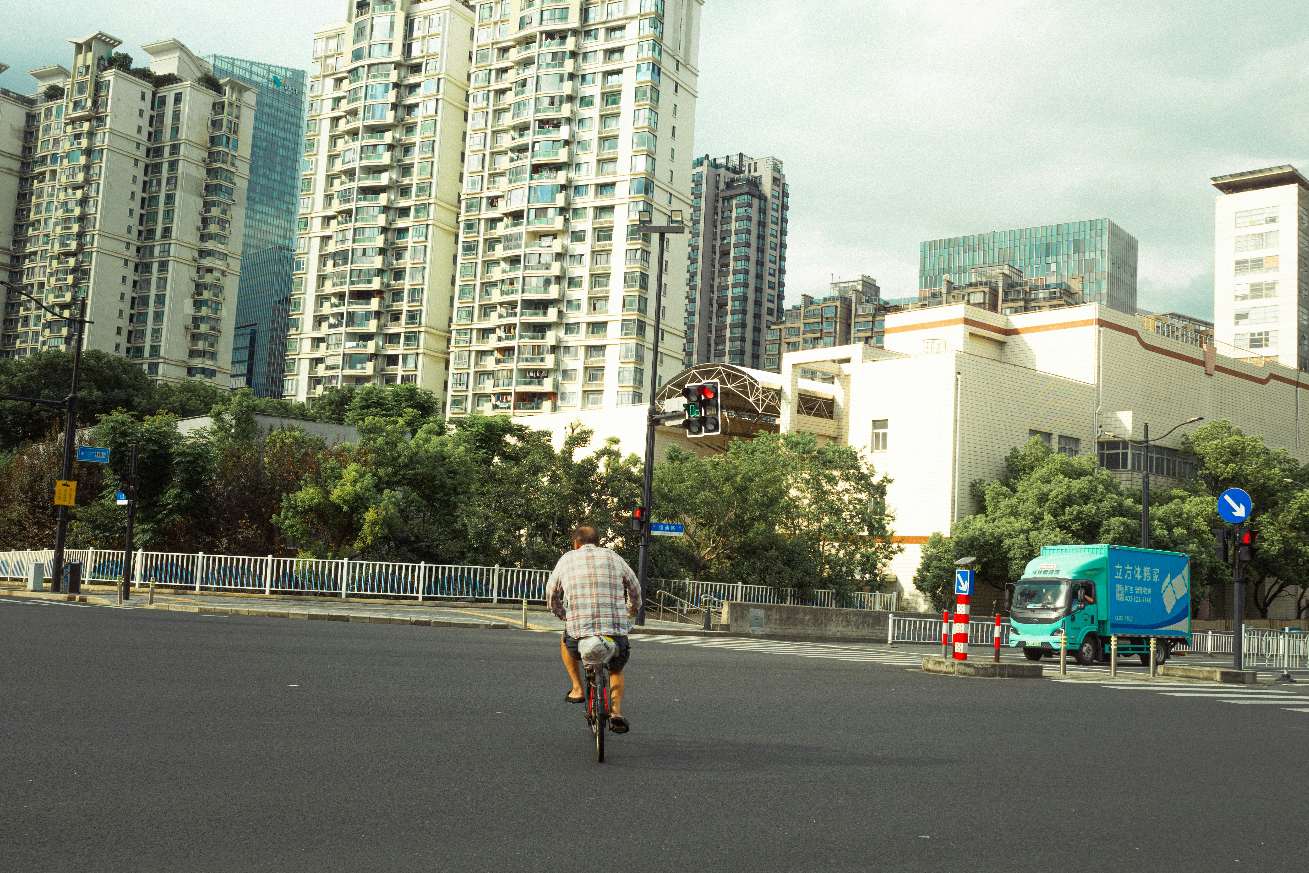Person cycling on a teal road between high-rises