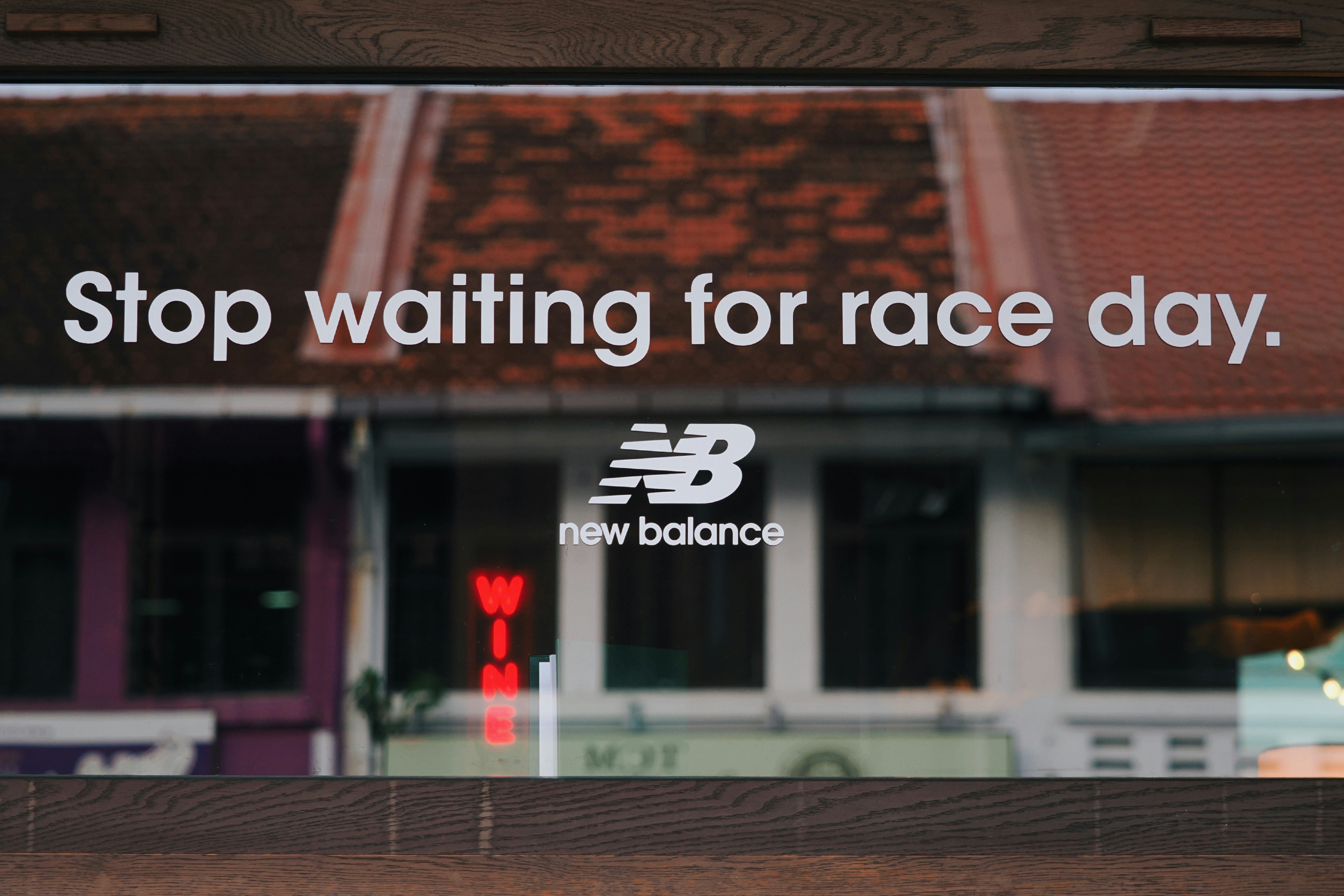 New Balance logo and text on a glass window with a red neon sign