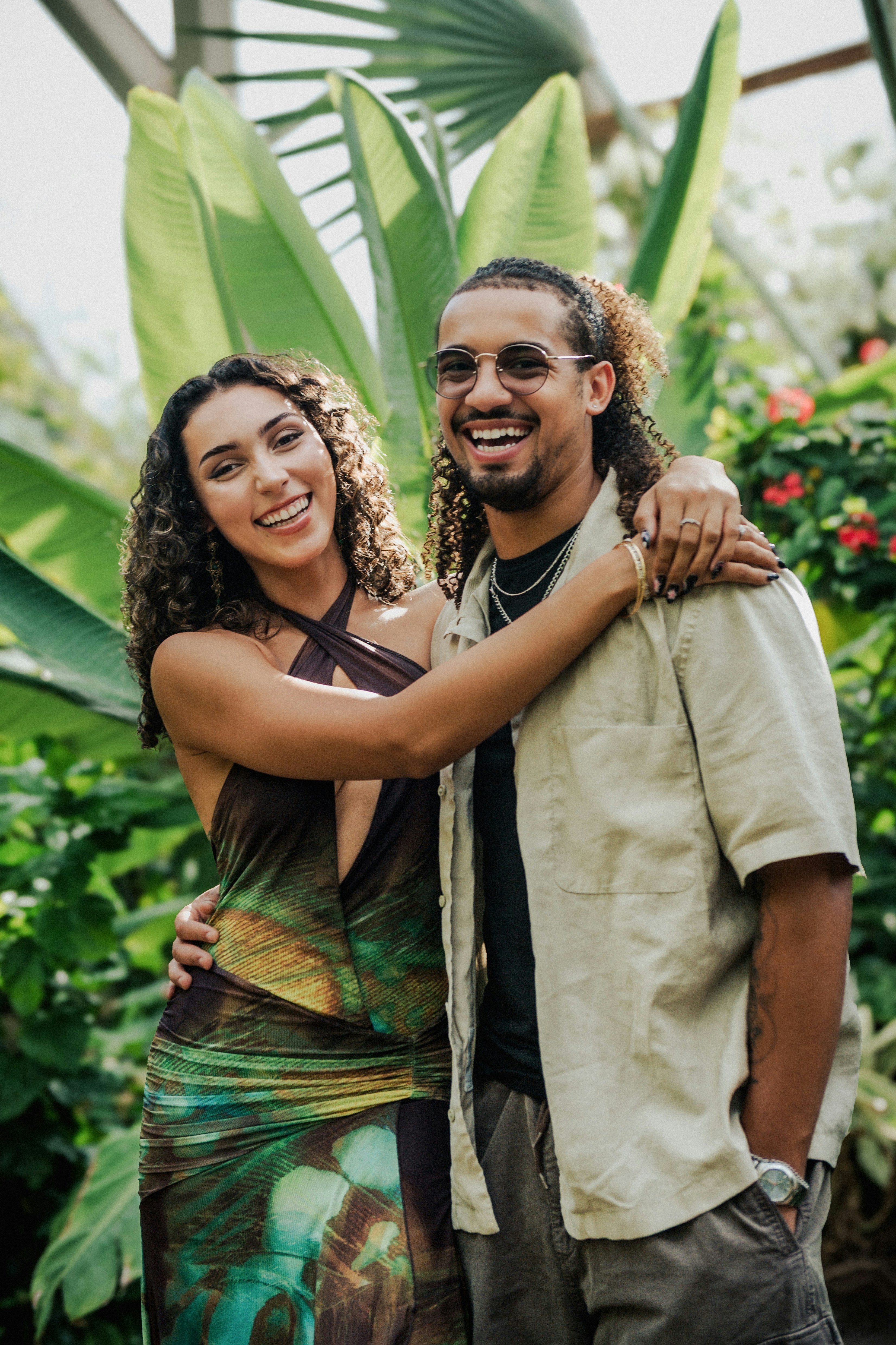 A woman and a man smiling with arms around each other in a greenhouse