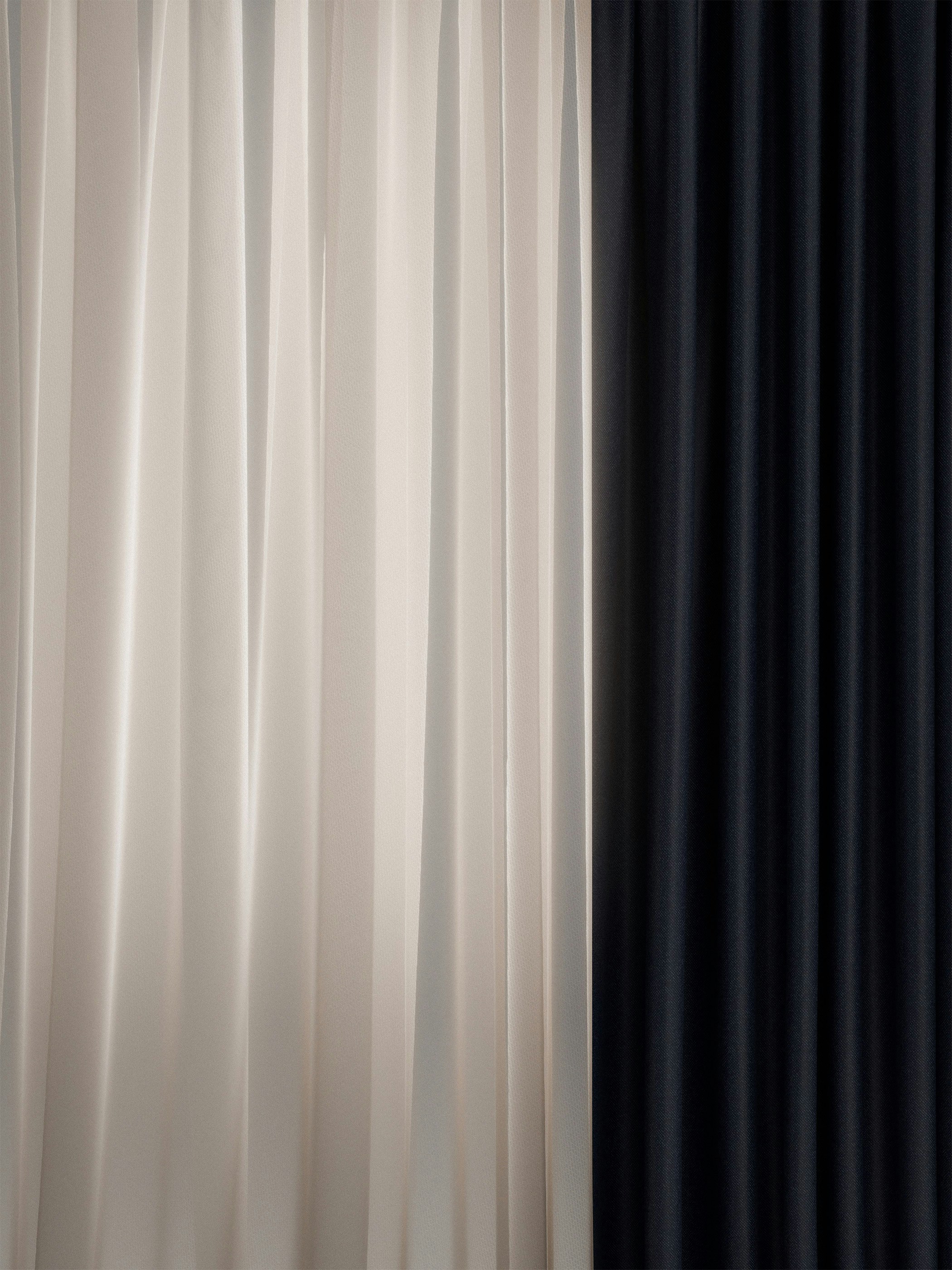 Vertical folds of white and black fabric curtains hanging side by side