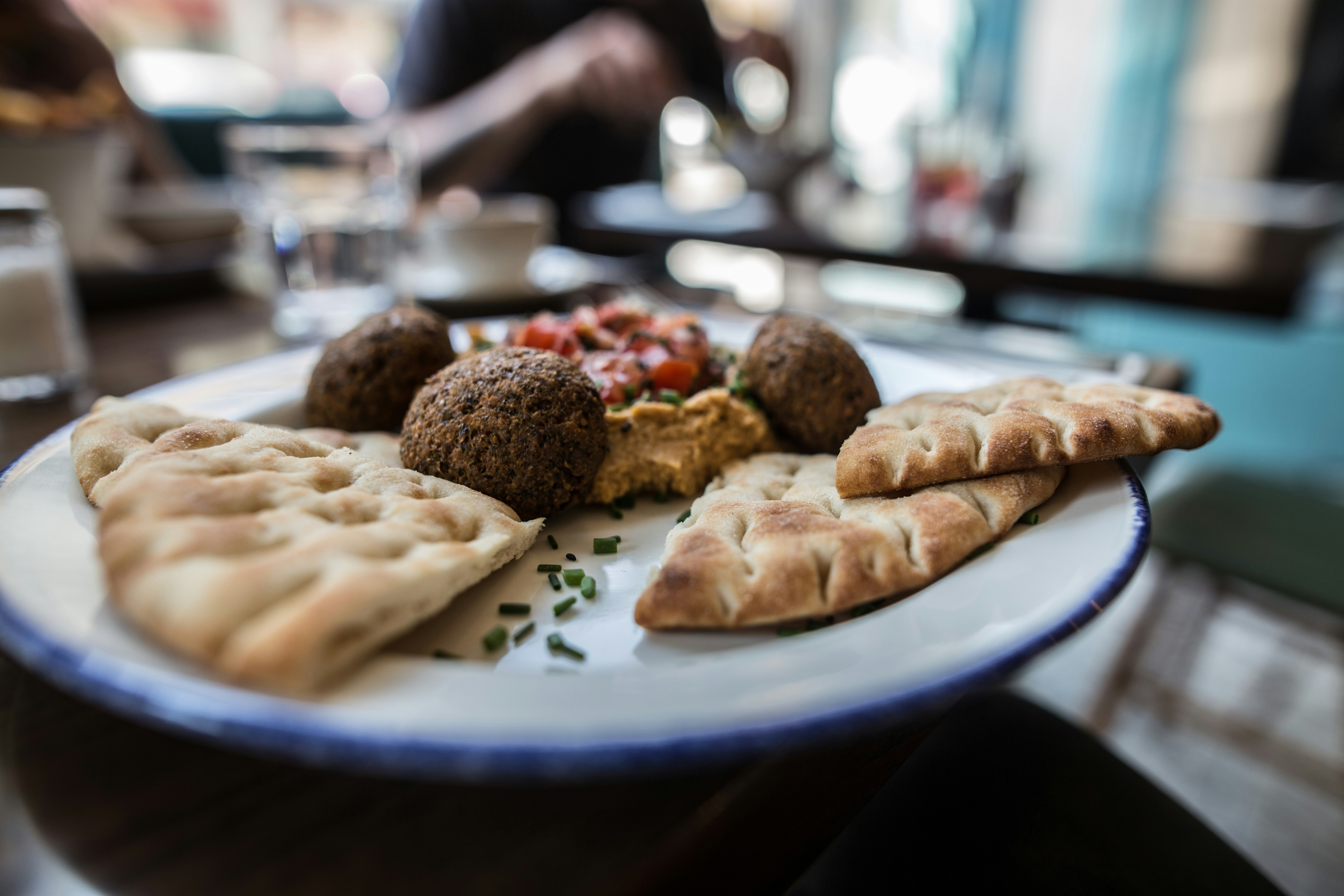 Falafel balls with hummus, pita bread, and chopped tomatoes on a white plate