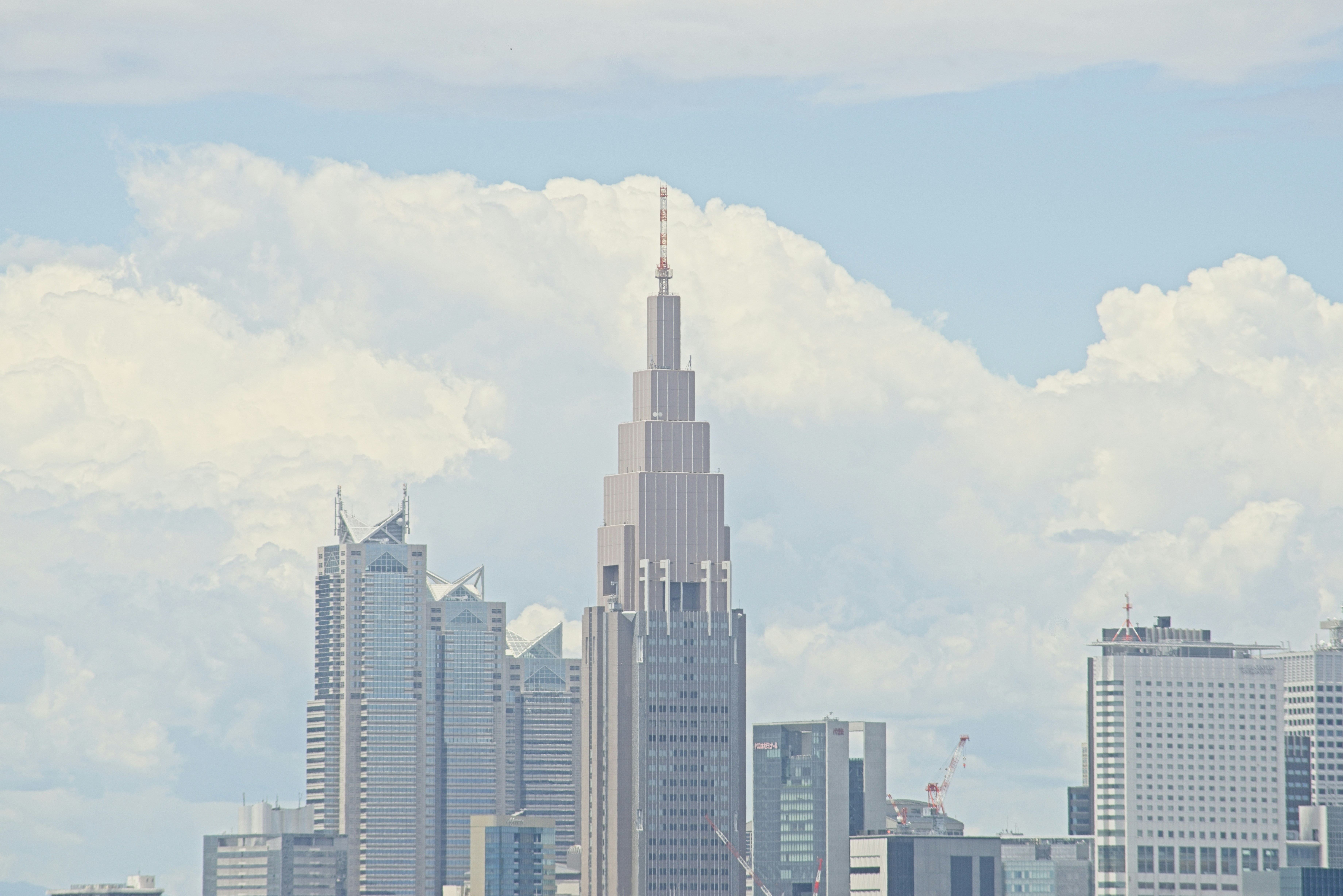 The NTT Docomo Yoyogi Building rising above the Tokyo skyline under a cloudy sky