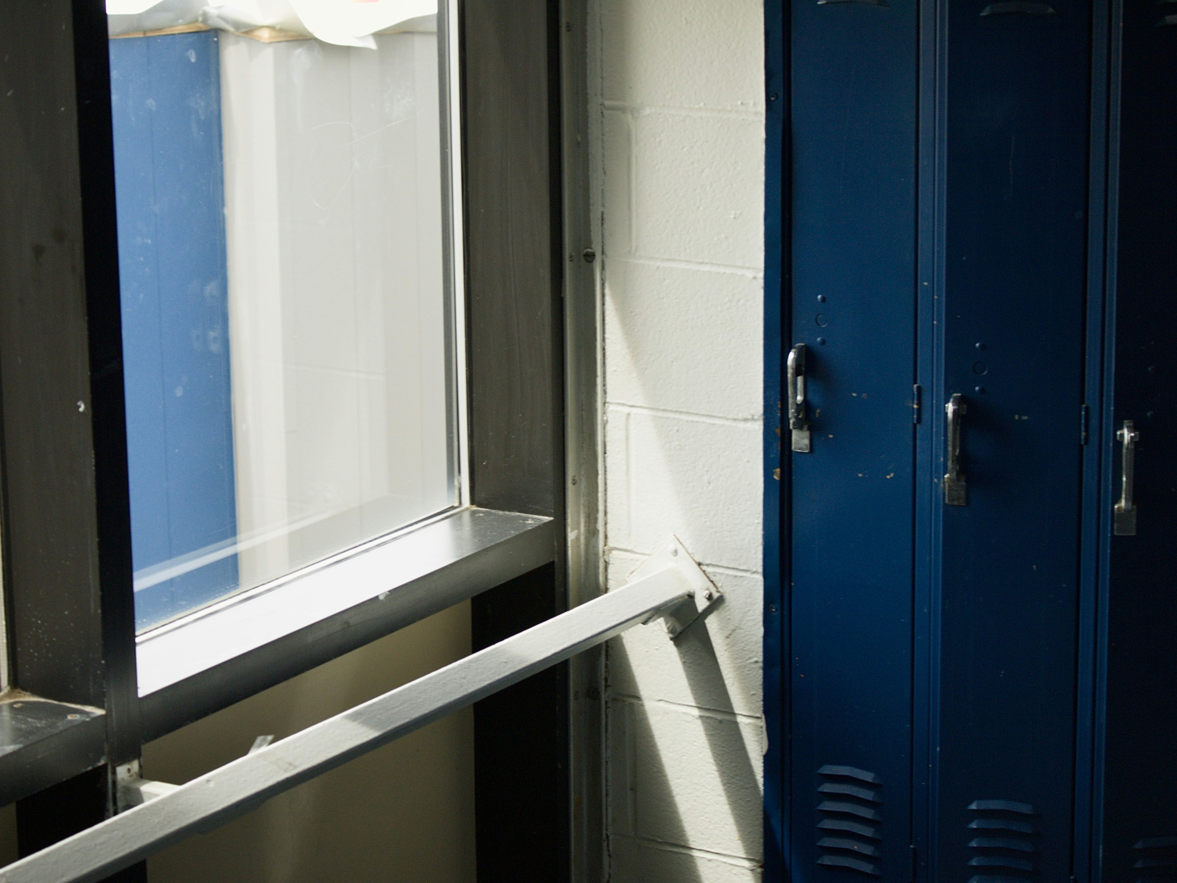 Blue metal school lockers beside a white cinder block wall and a sunlit window