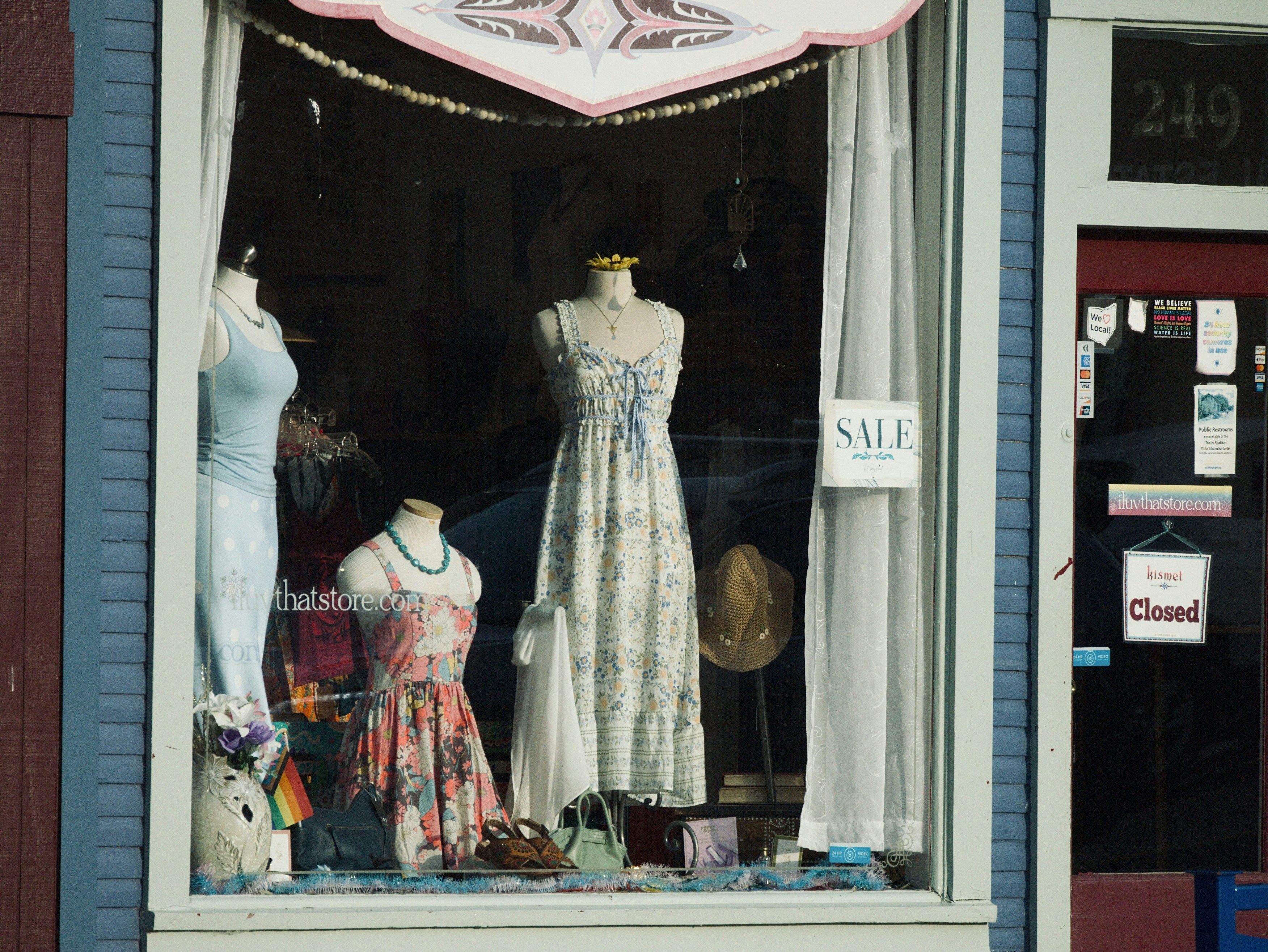 Three mannequins in summer dresses in a shop window