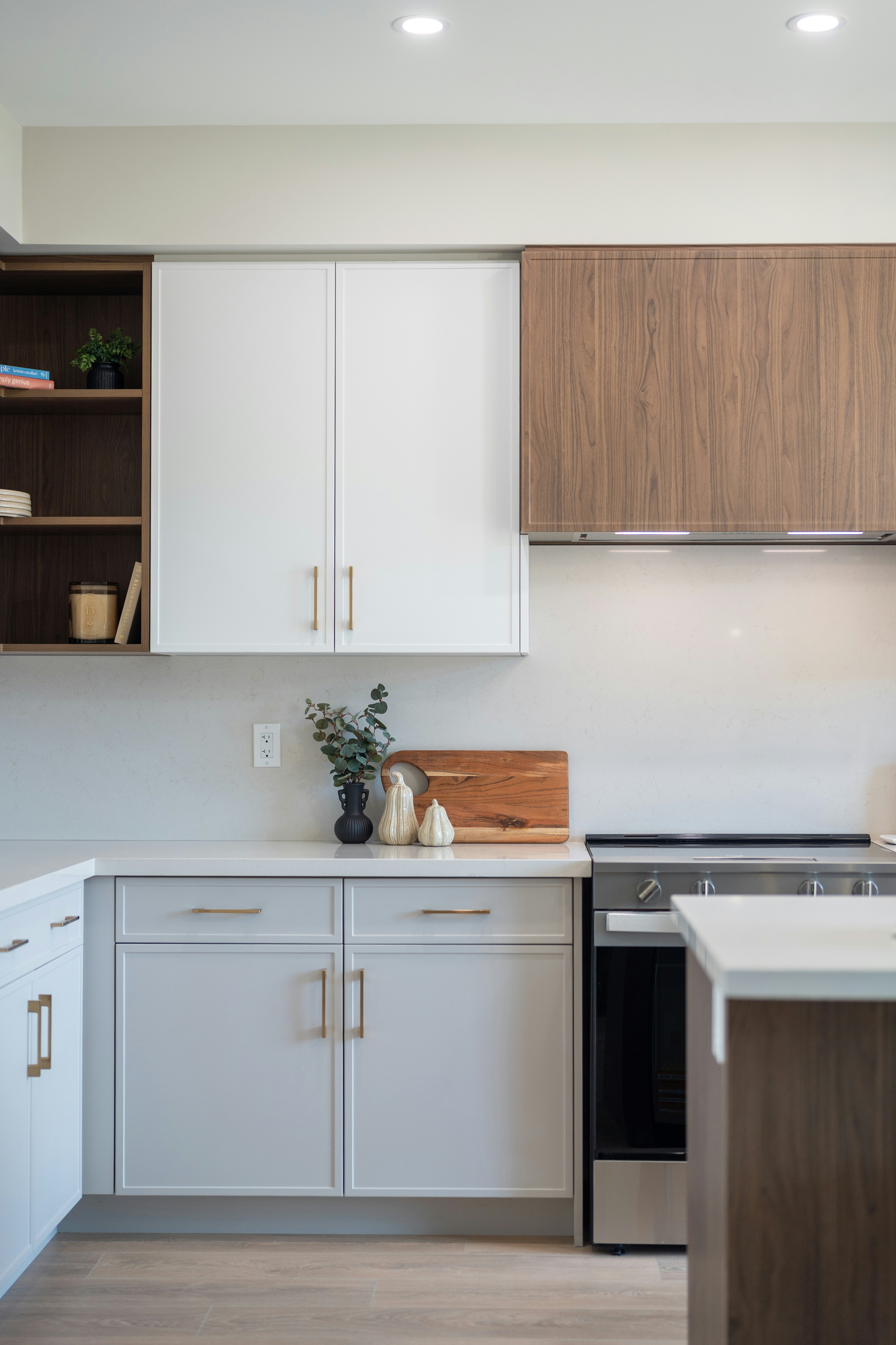 A kitchen with white and wood cabinets, a white countertop, and a stove