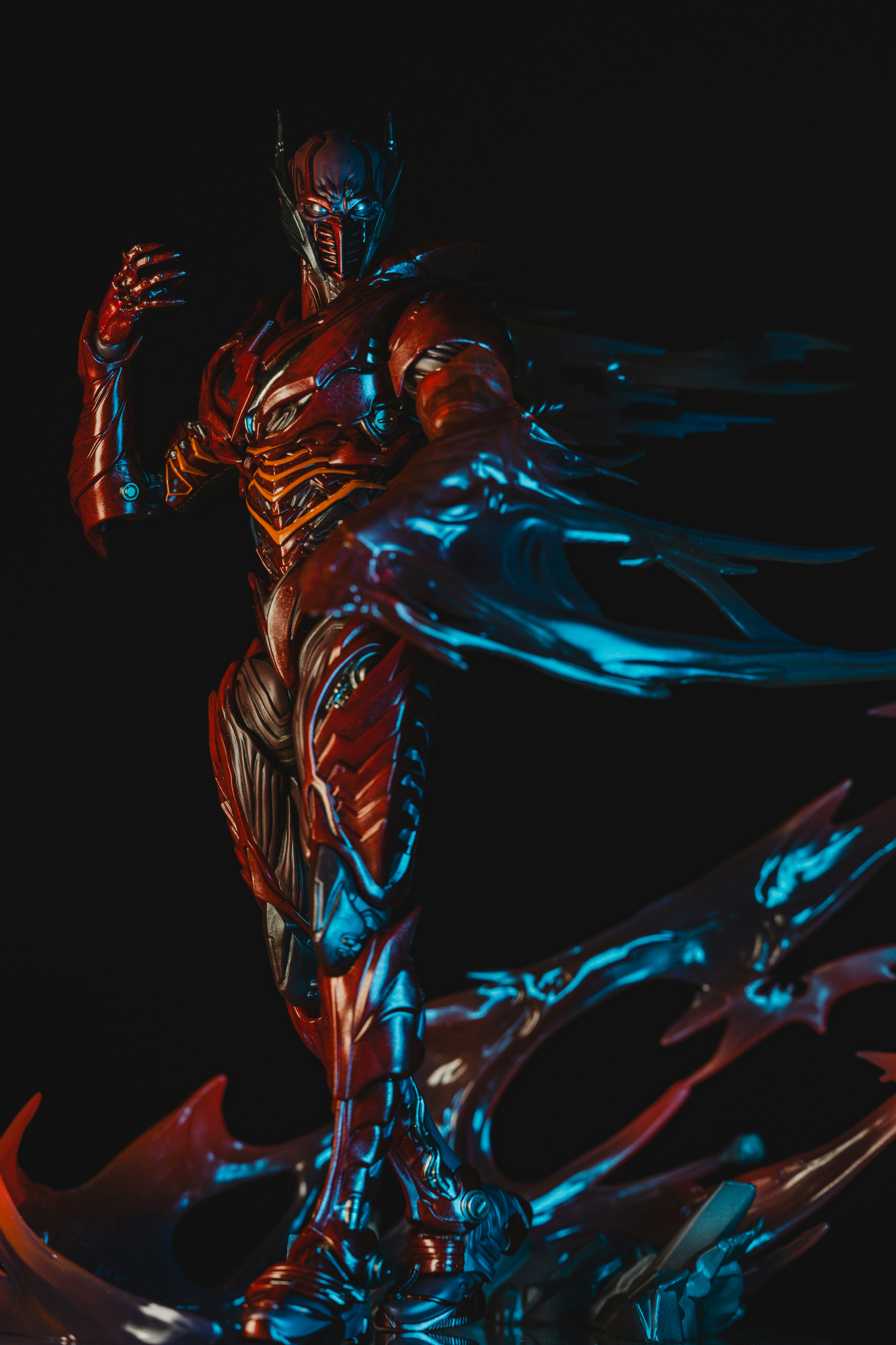 A red armored action figure with blue energy effects against a black background