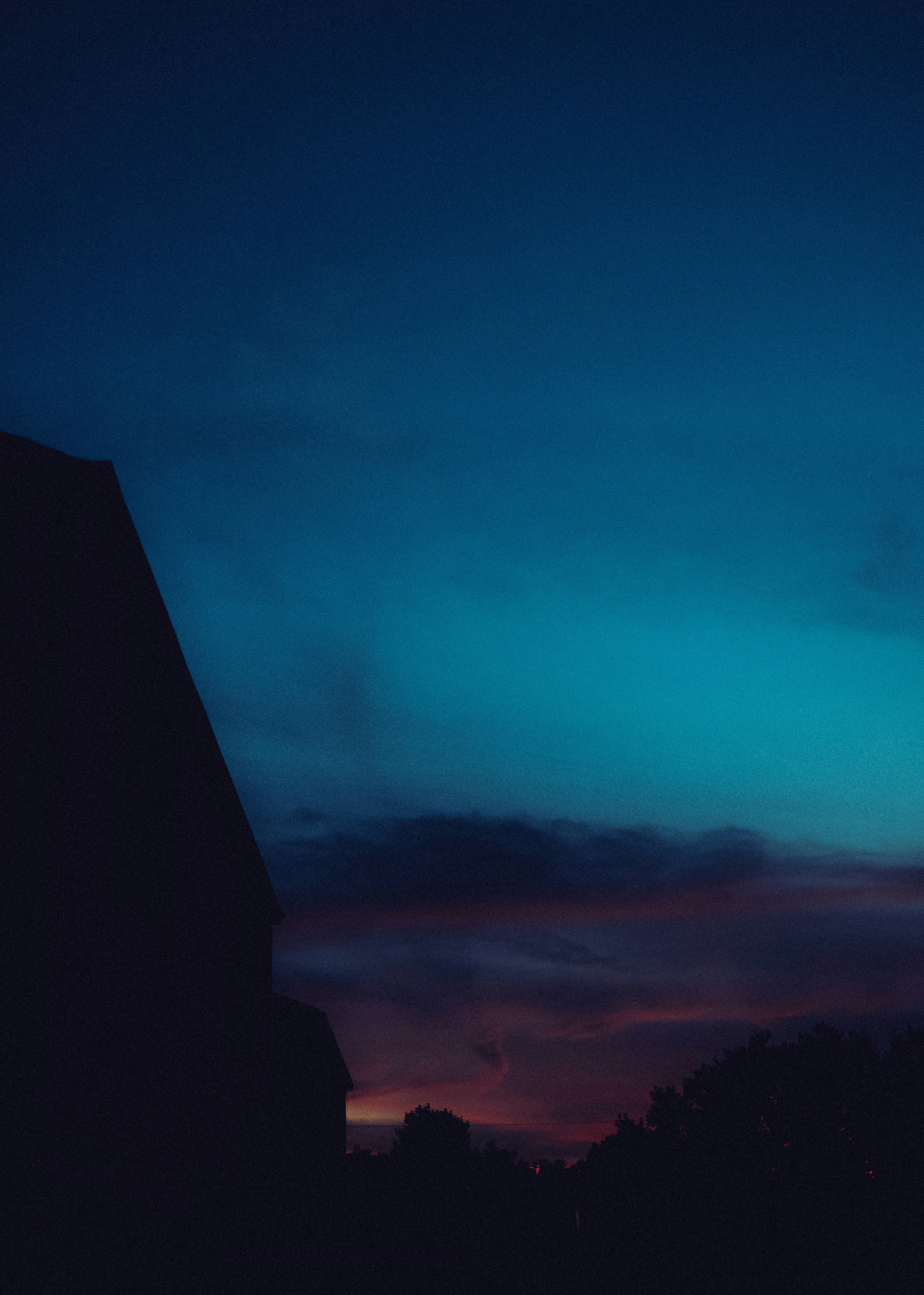 A dark silhouette of a building against a deep blue and purple sky