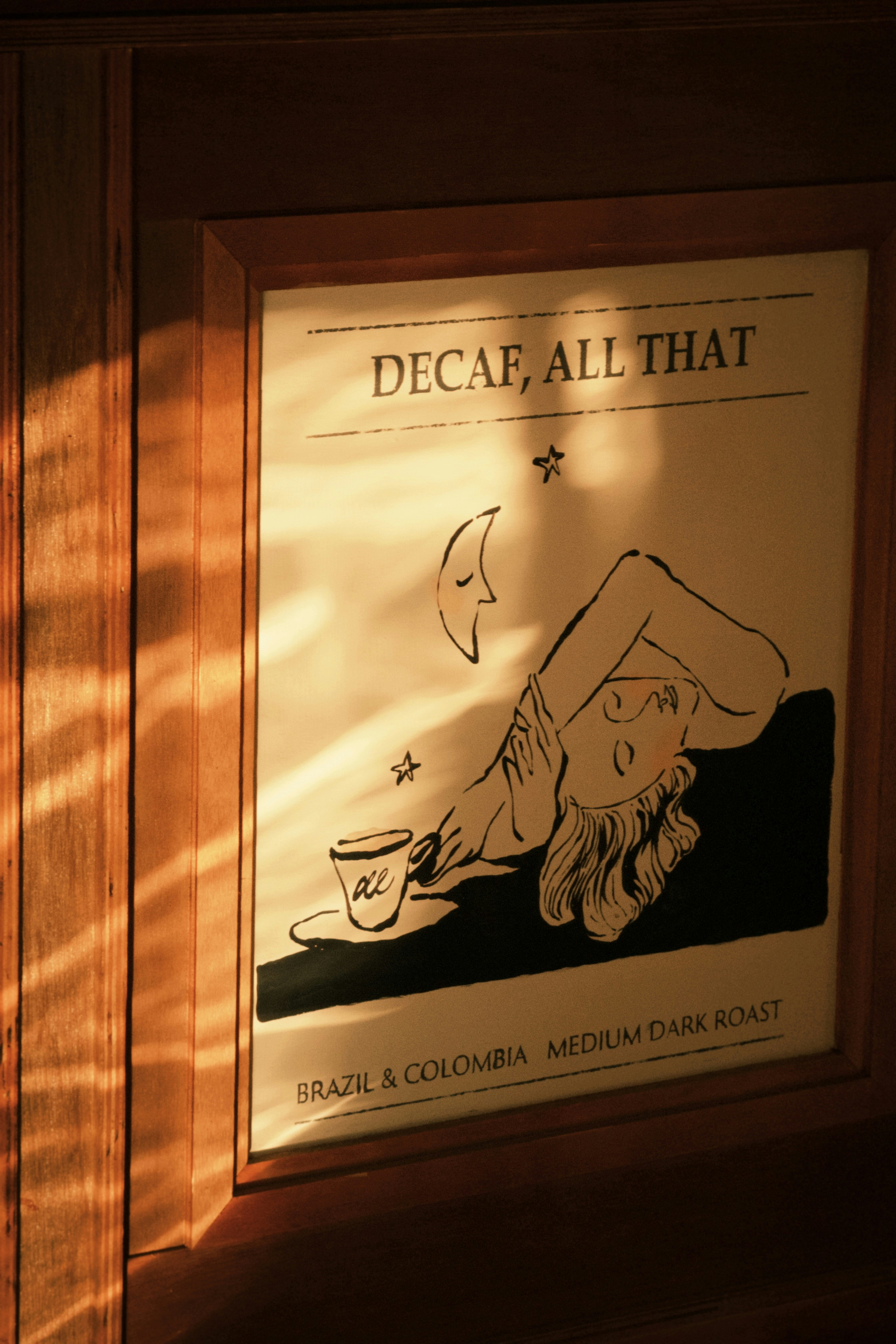 Photo of A framed print reading DECAF, ALL THAT with a person and coffee cup by ModernShoot