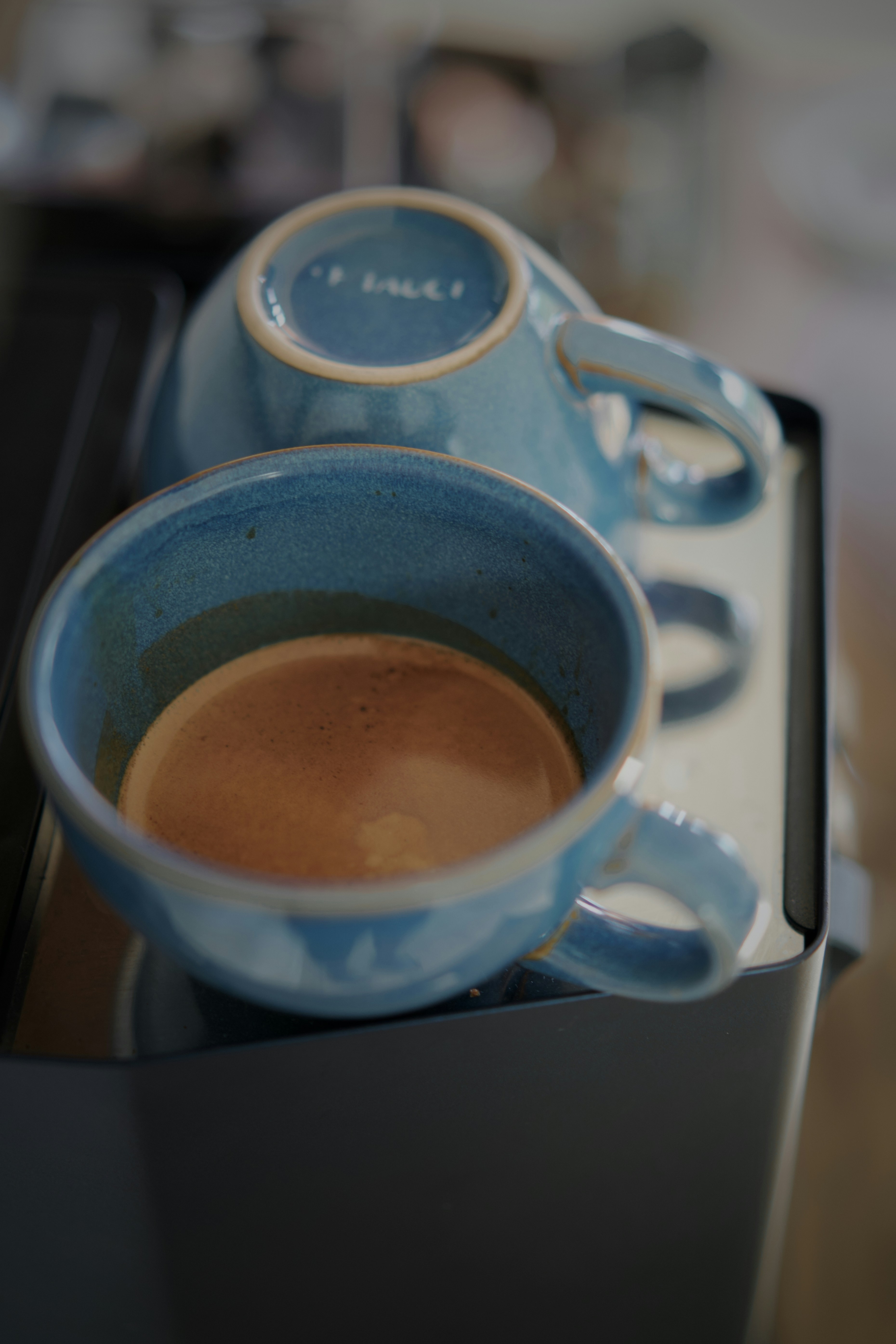Morning light and shadow falling across coffee in a blue ceramic mug.