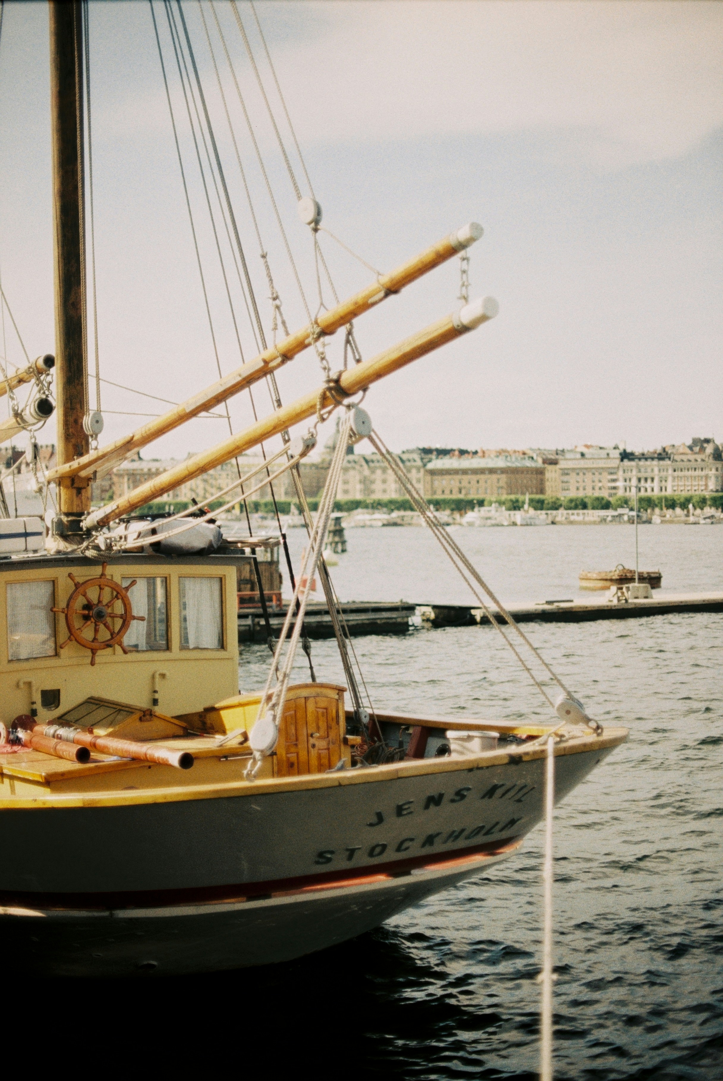 A wooden boat named Jens Kil docked in the harbor of Stockholm