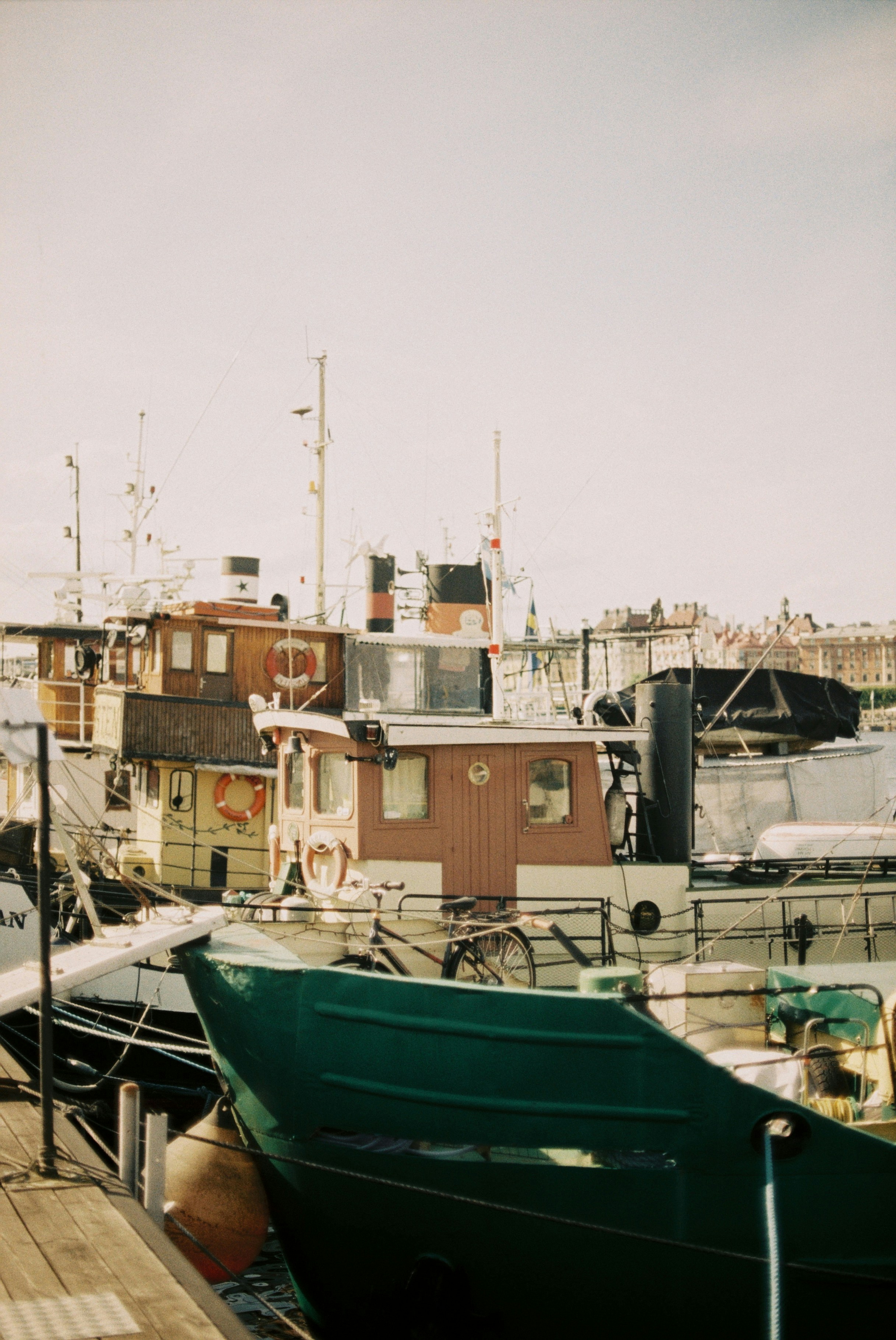 Several vintage boats moored at a wooden dock with a bicycle on deck