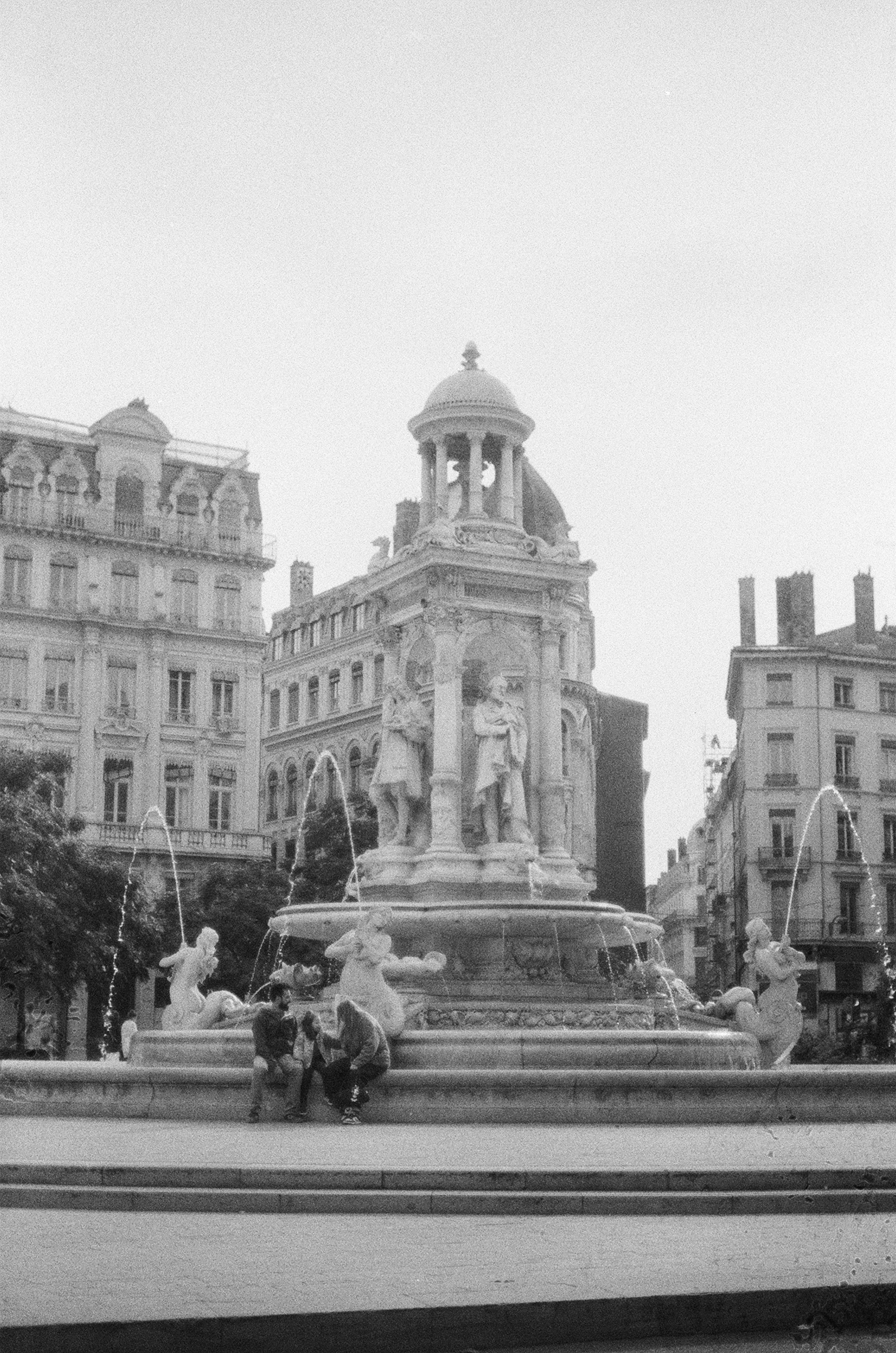 People sitting on the edge of the Jacobins fountain in Lyon, France