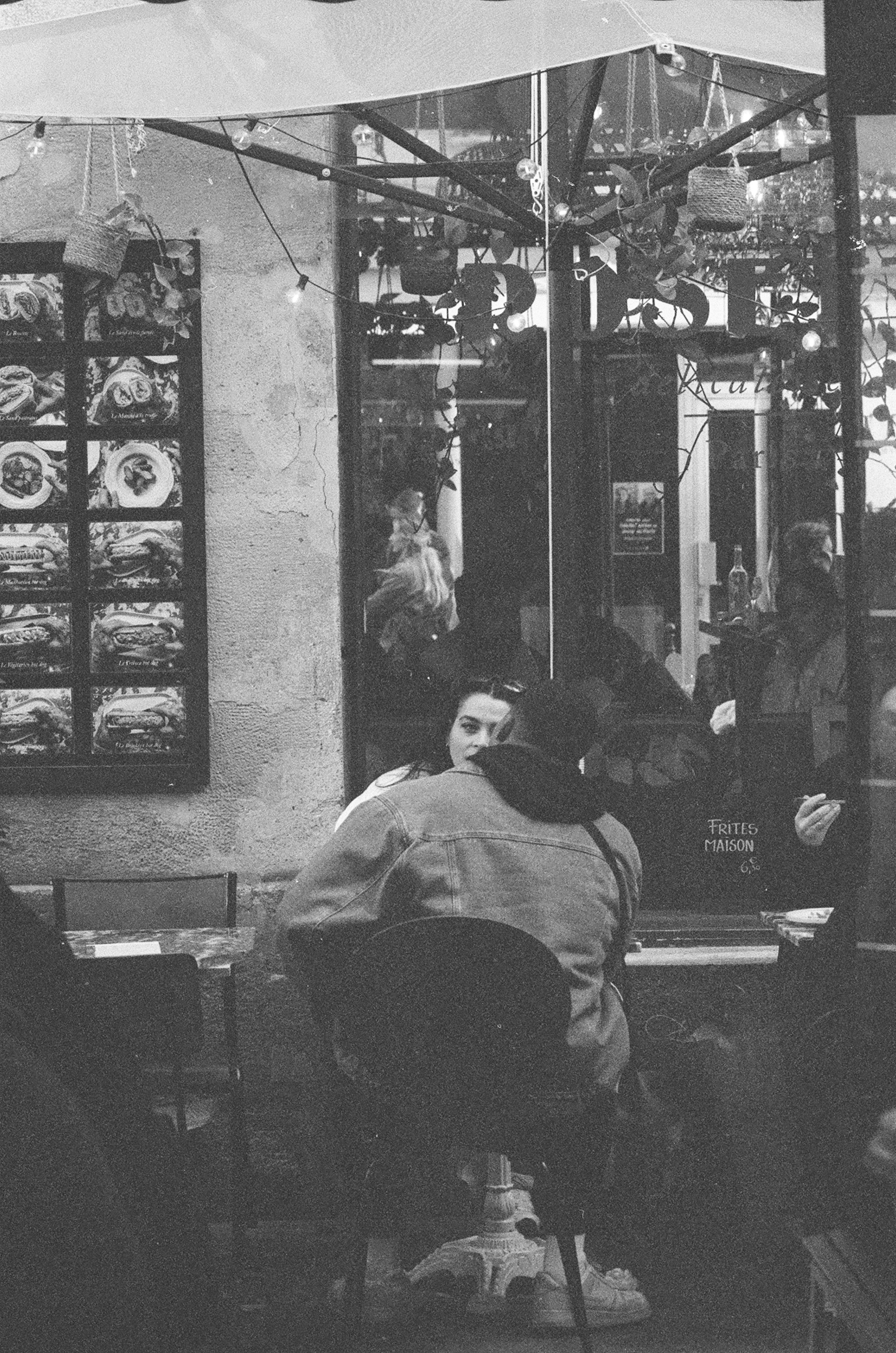 Two people sitting at a small table outside a cafe in Paris