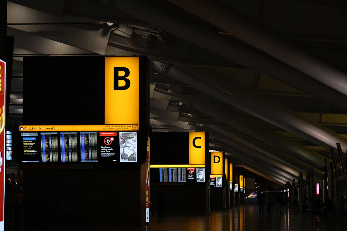 Papan penunjuk check-in kuning di terminal bandara yang remang