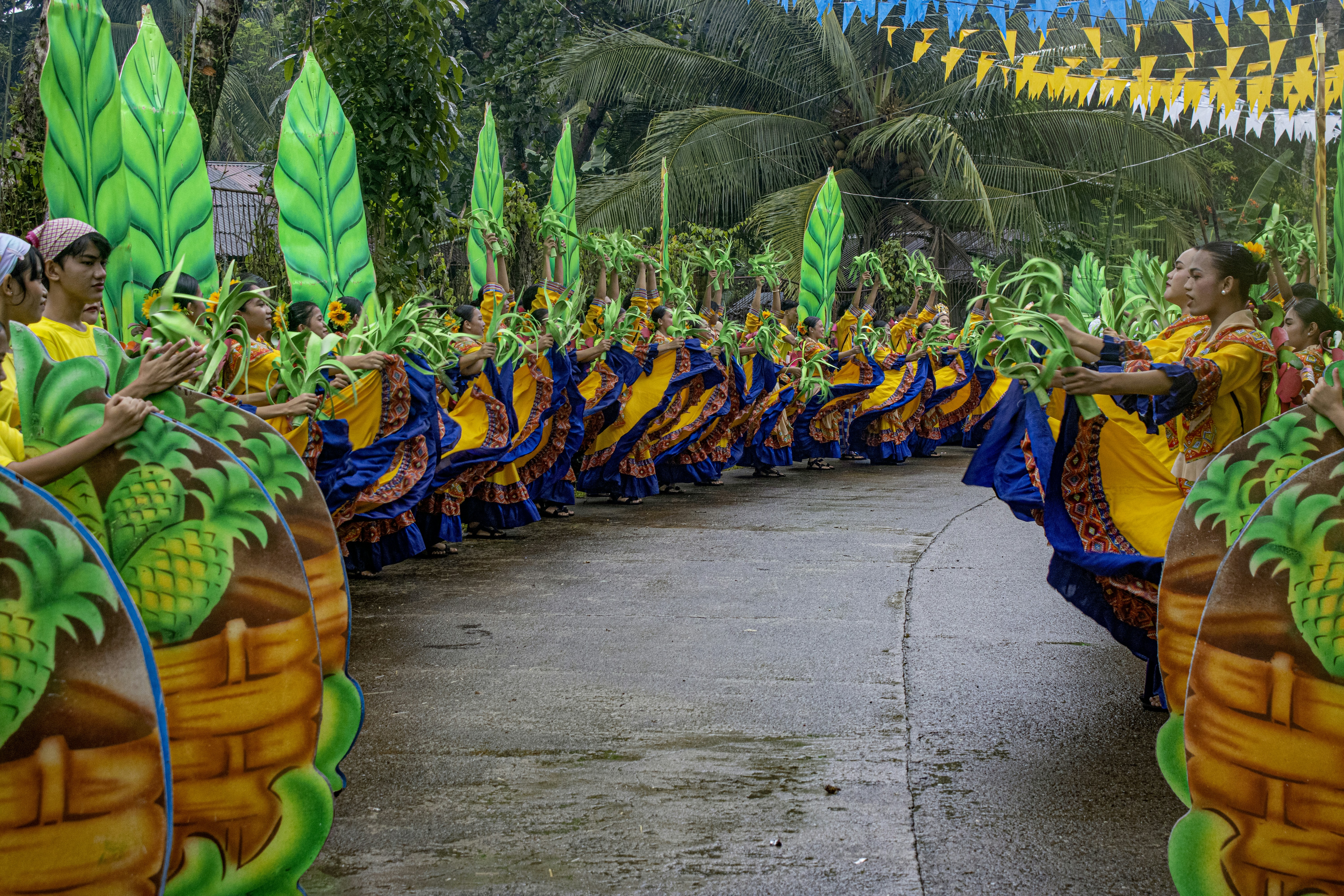A group of dancers in yellow and blue dresses performing on a street
