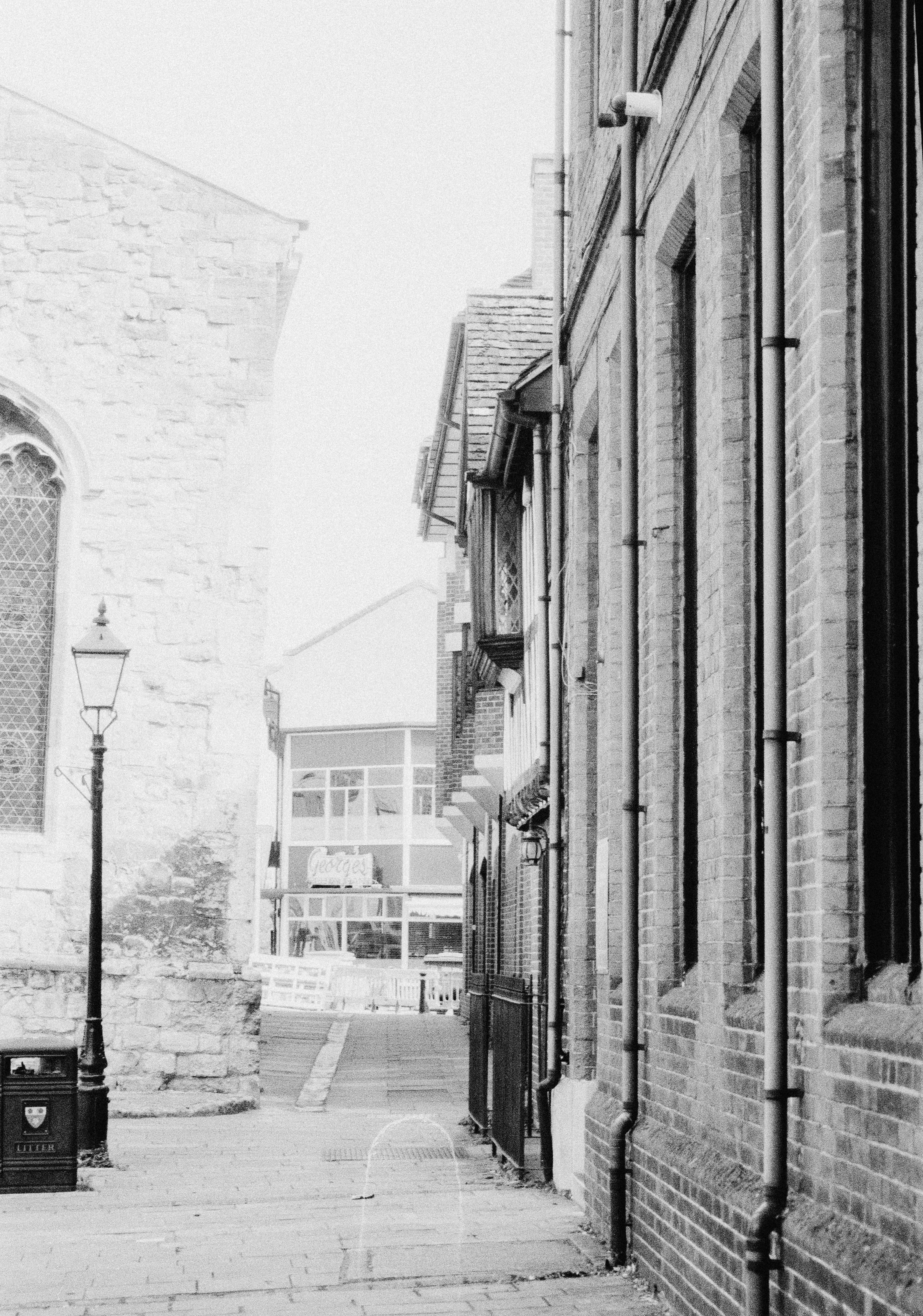 A narrow stone alleyway with a vintage lamp post and brick buildings