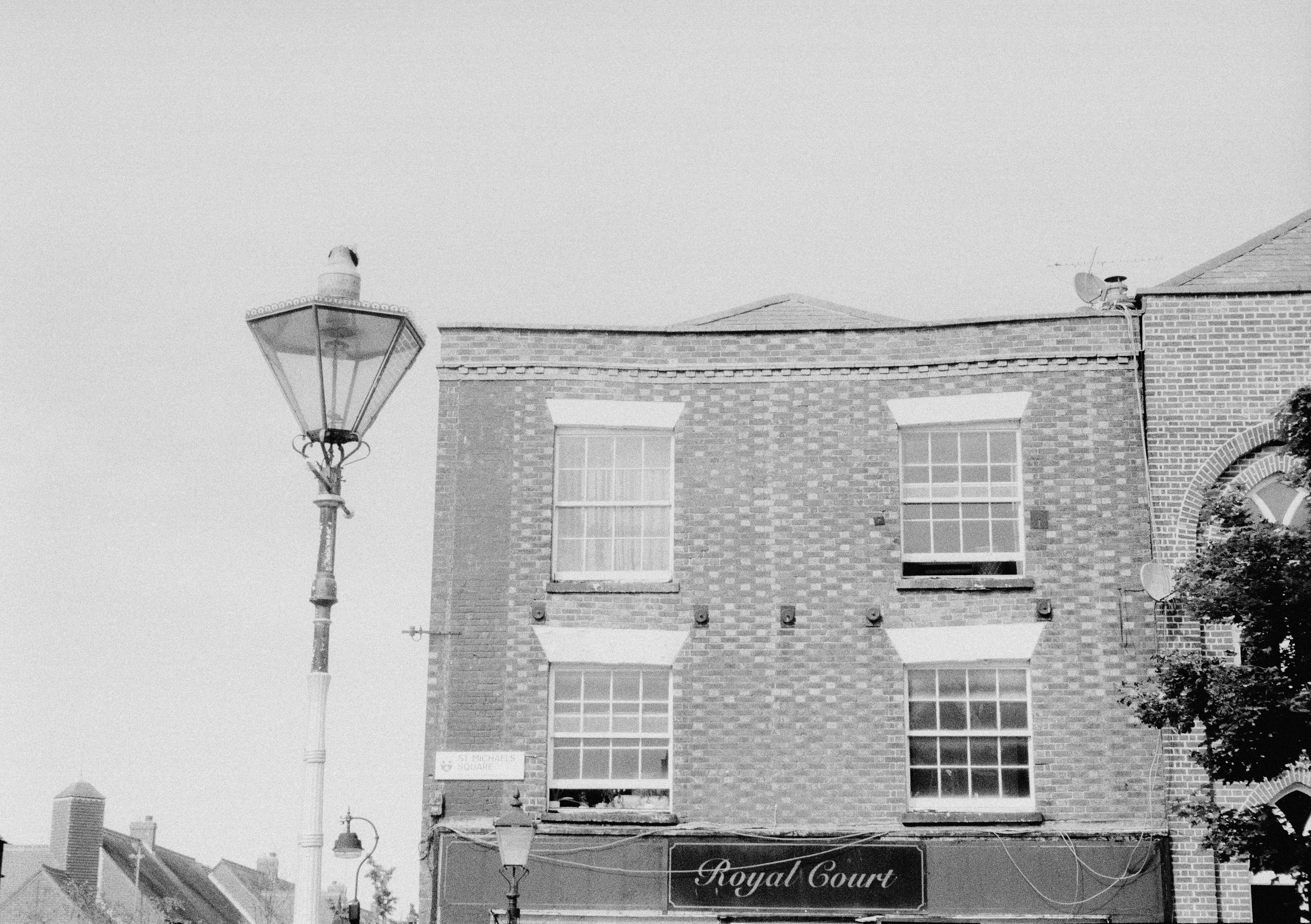 A brick building with a sign reading Royal Court beside a vintage street lamp