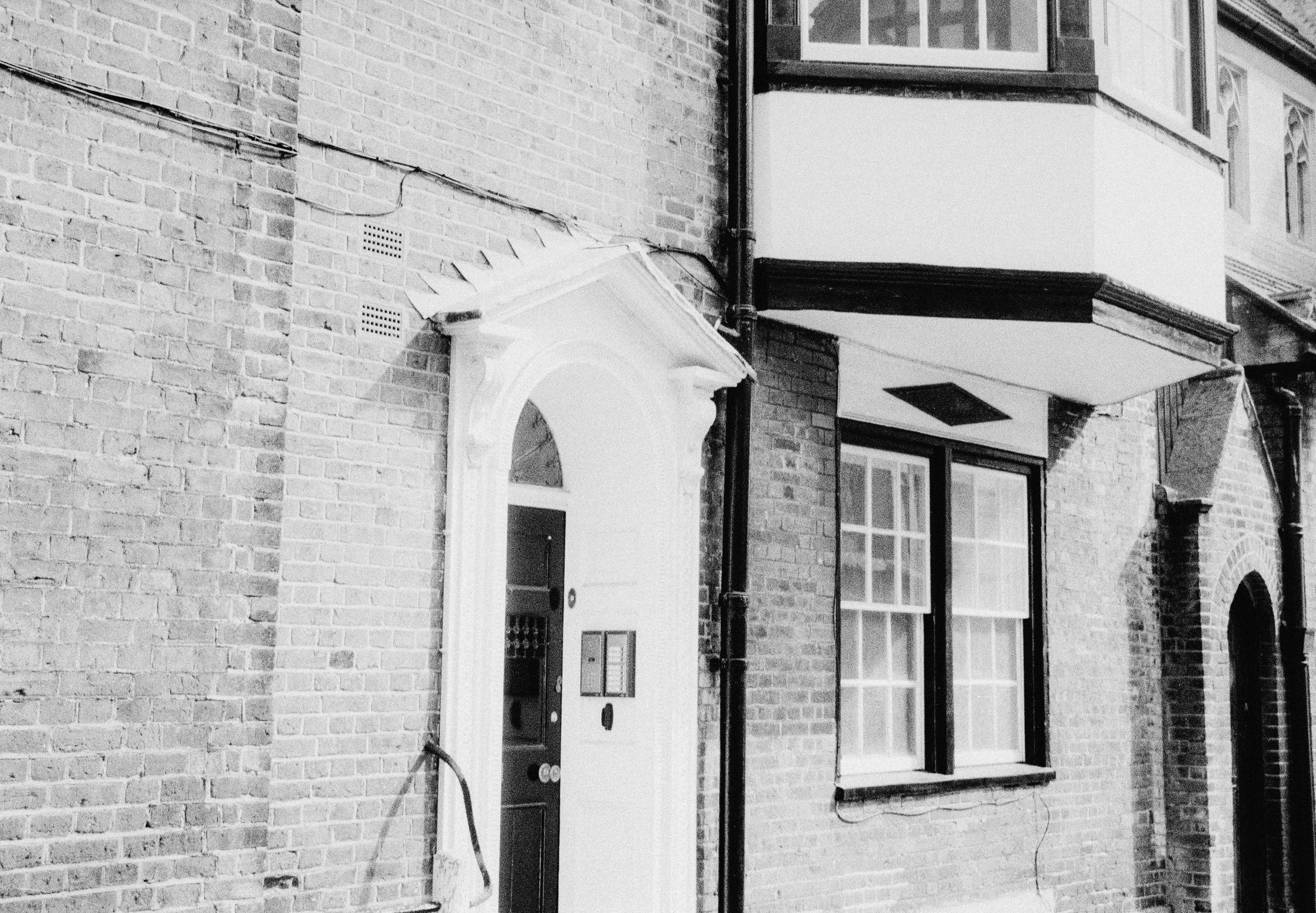 A black and white view of a brick building with a white arched doorway